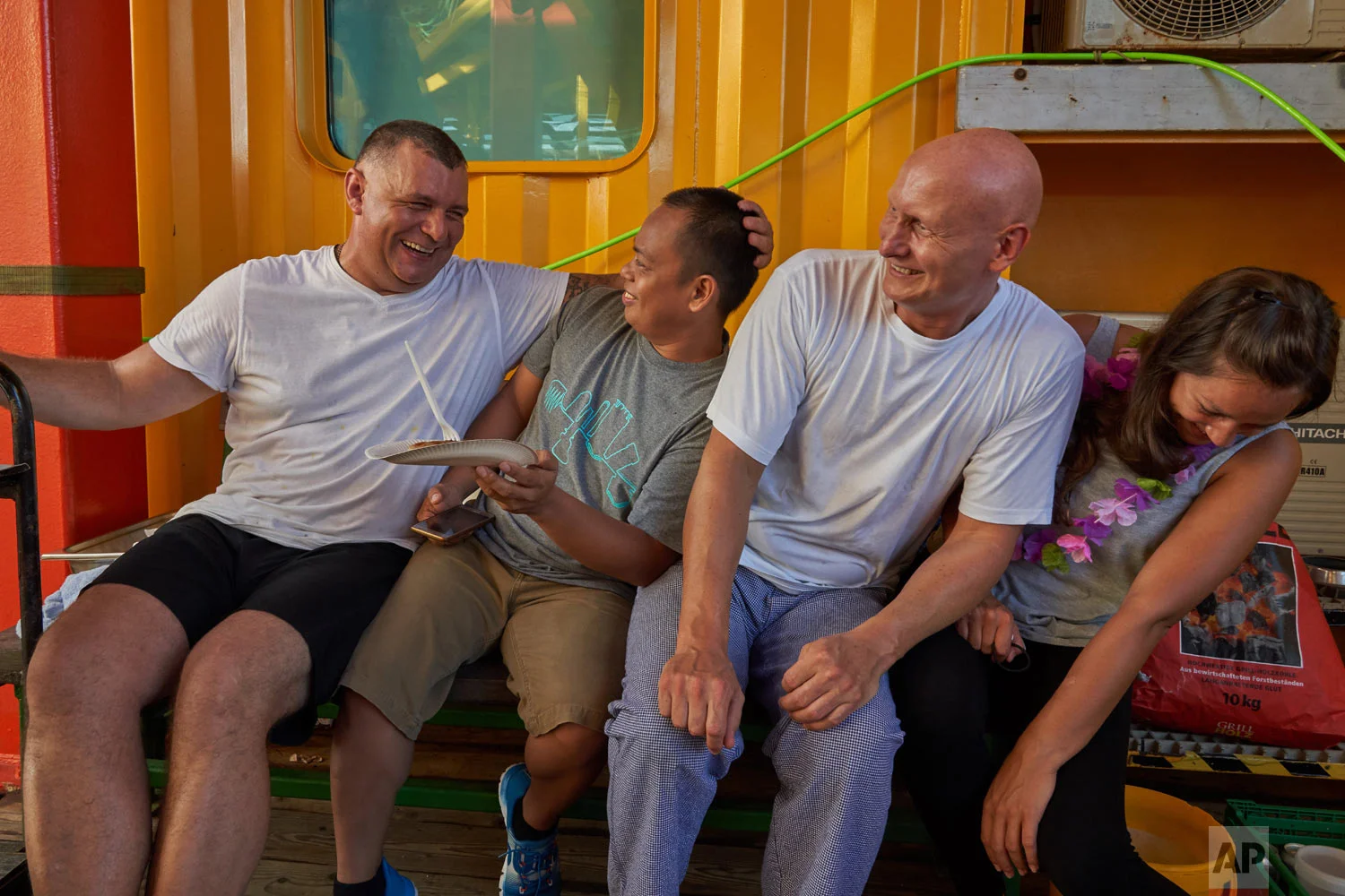 A galley crew relax after preparing a barbecue for the researchers onboard the vessel Ocean Zephyr in the waters of the Seychelles, April 2, 2019. (AP Photo/David Keyton)