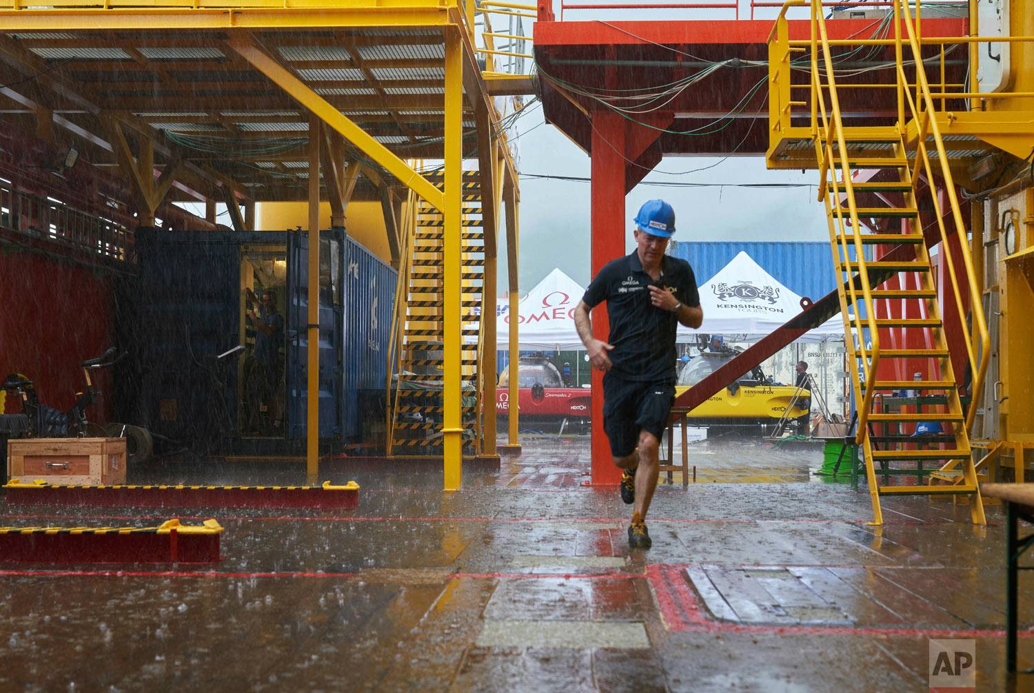 Nekton Mission Director, Oliver Steeds, runs across the deck of the Ocean Zephyr, March 4, 2019, during a rainstorm that momentarily paused preparations for the 7-week long expedition. (AP Photo/David Keyton)