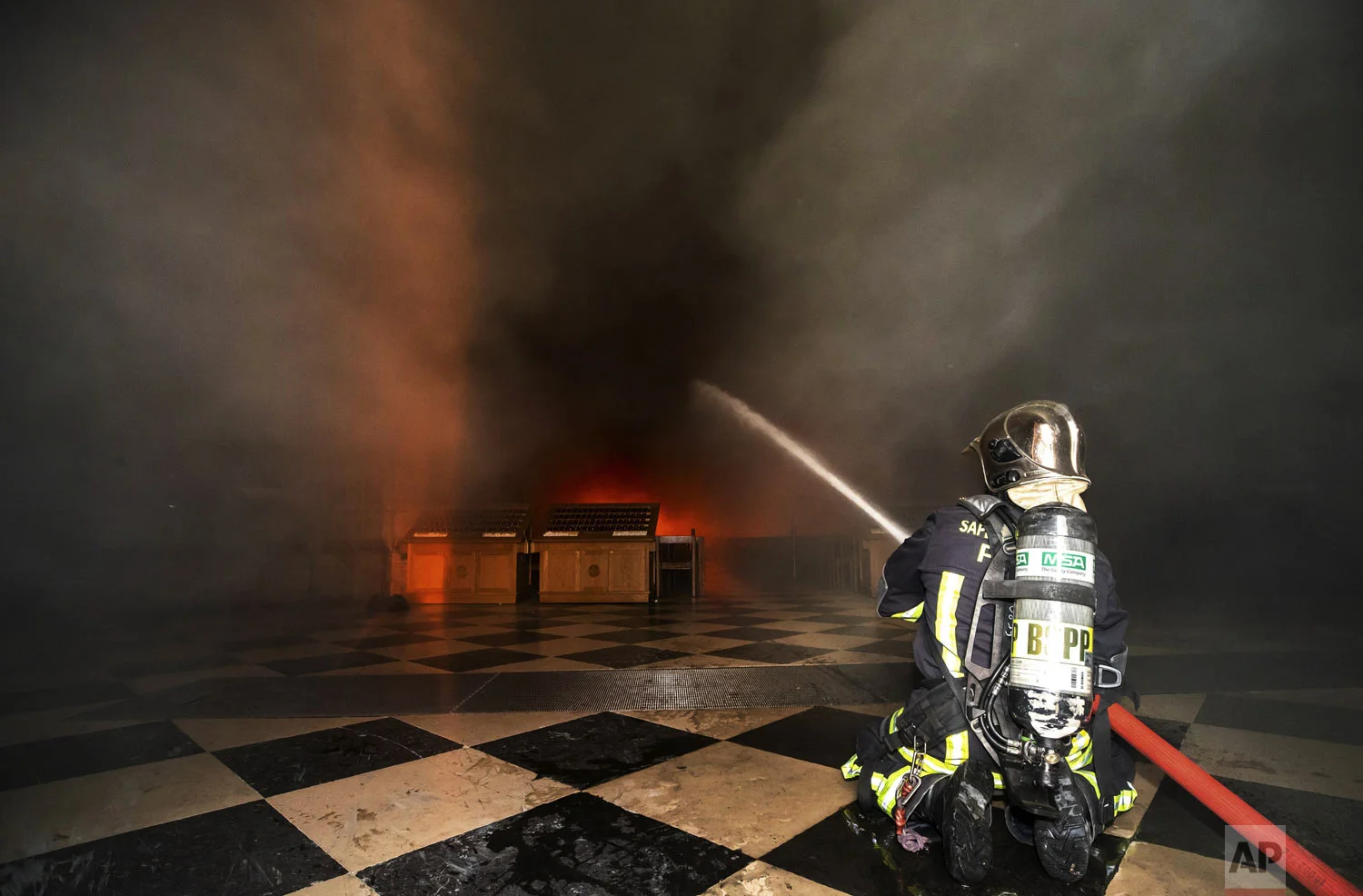 In this photo provided by the Paris Fire Brigade, firefighters spray water inside the Notre Dame cathedral, Monday April 15, 2019. An inferno that raged through the historic site for more than 12 hours destroyed its spire and its roof but spared its twin medieval bell towers, and a frantic rescue effort saved the monument's "most precious treasures," including the Crown of Thorns purportedly worn by Jesus, officials said Tuesday. (Benoit Moser/BSPP via AP)