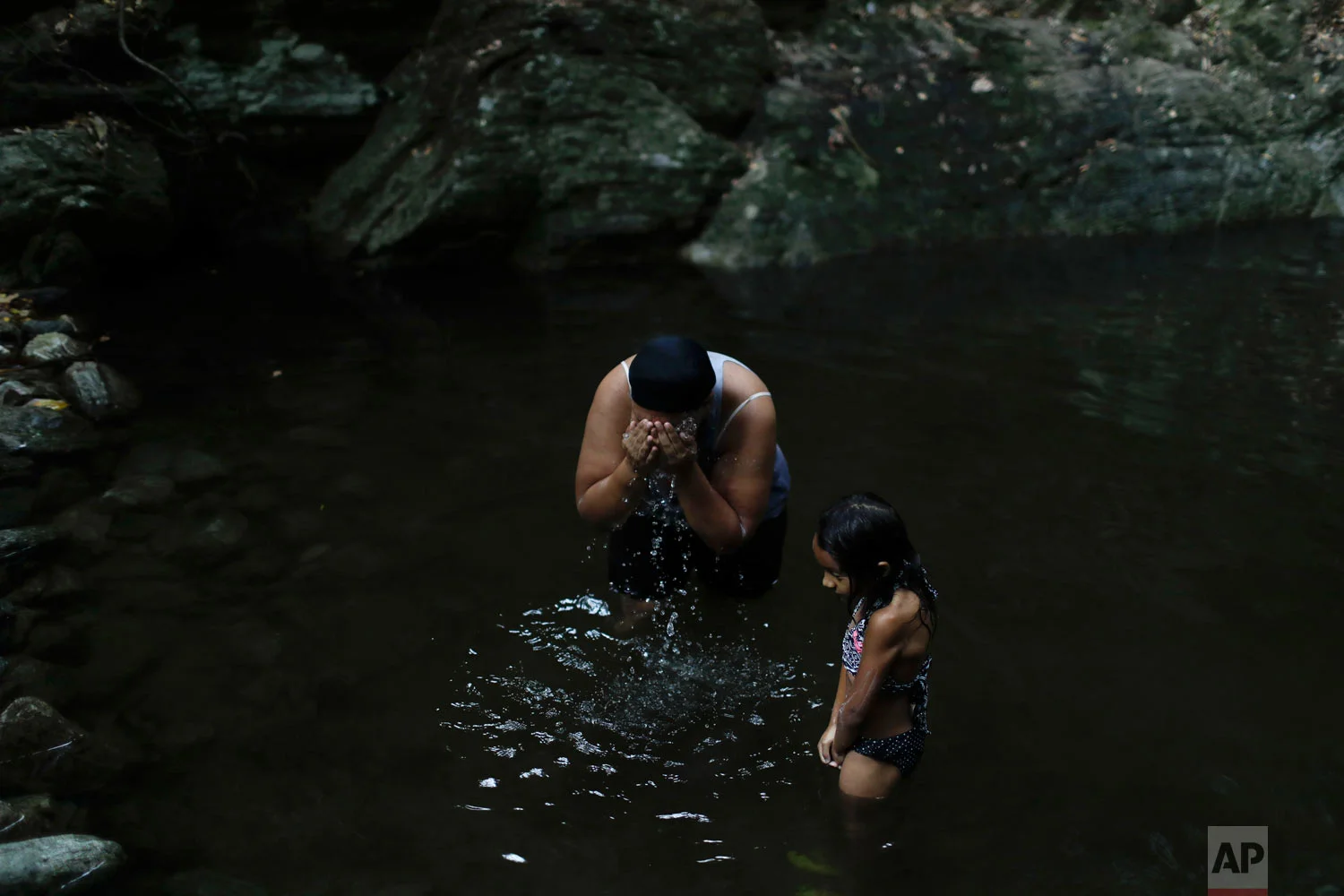 Liz Vargas and her niece Camila Vargas bathe in Avila National Park in Caracas, April 4, 2019. Vargas said she hasn't had running water at home for the previous 15 days, and this was the first time she'd come to bathe where she used to swim for fun. (AP Photo/Natacha Pisarenko)