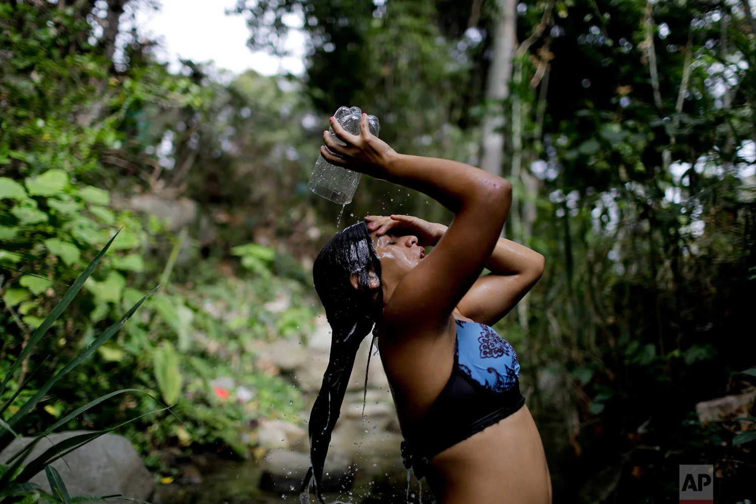  Barbara Hernandez washes her hair in a natural brook in Caracas, Venezuela, Wednesday, April 3, 2019. Hernandez said she used to wash her hair more often but now that she has no running water at home, she washes her hair just once a week here as her
