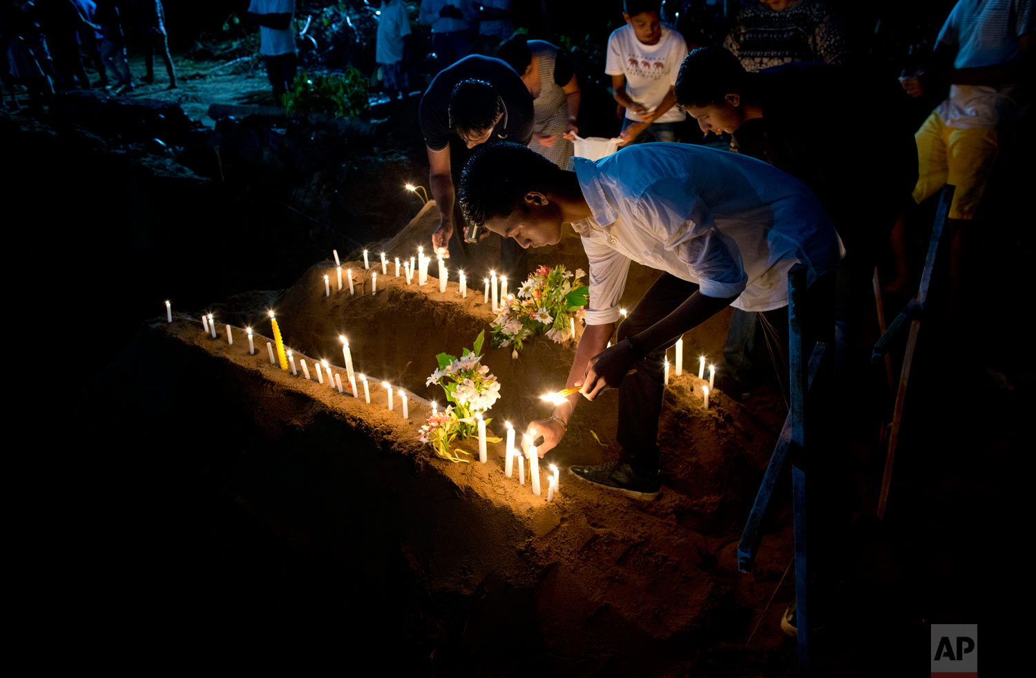 Relatives light candles after burial of three victims of the same family, who died at Easter Sunday bomb blast at St. Sebastian Church in Negombo, Sri Lanka, April 22, 2019. (AP Photo/Gemunu Amarasinghe)