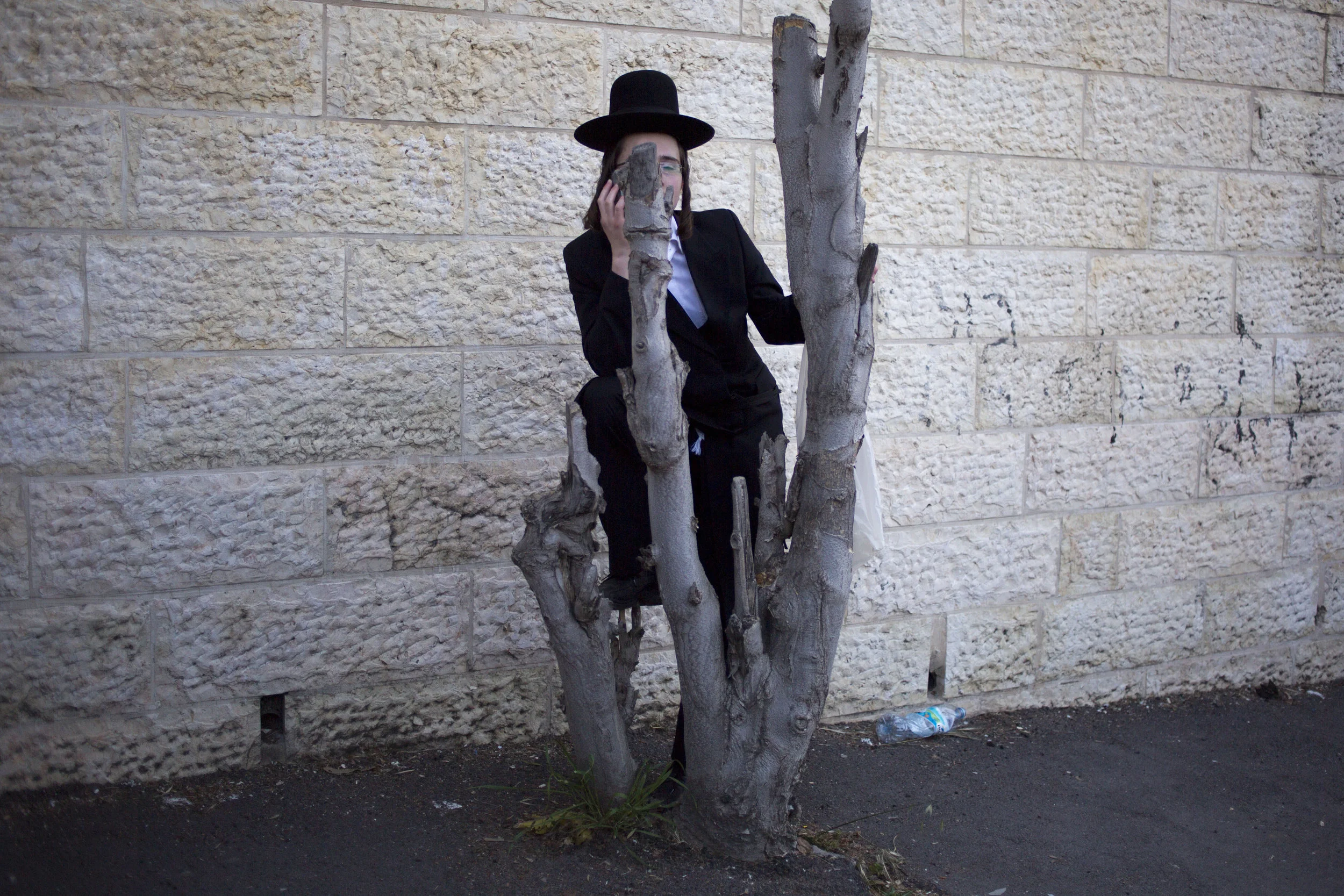 An Ultra-Orthodox Jew watches the funeral procession of Rabbi of the Kaliv Hasidic dynasty and Holocaust survivor Menachem Mendel Taub in Jerusalem, Sunday, April 28, 2019. (AP Photo/Ariel Schalit)
