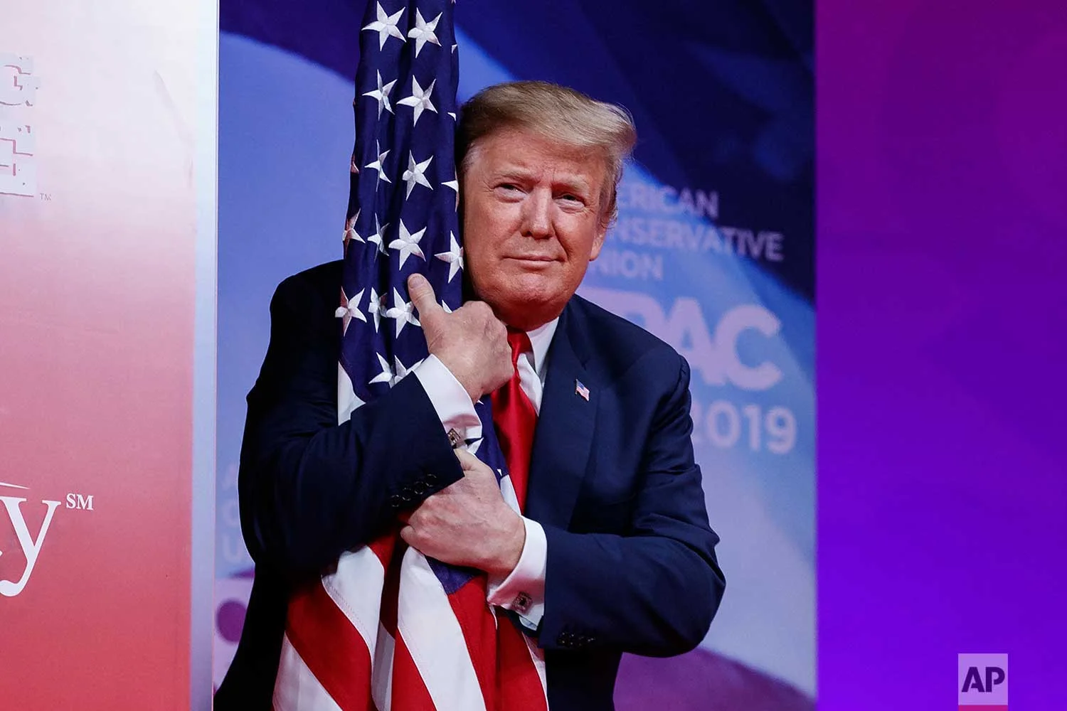 President Donald Trump hugs the American flag as he arrives to speak at Conservative Political Action Conference, CPAC 2019, in Oxon Hill, Md., Saturday, March 2, 2019. (AP Photo/Carolyn Kaster)
