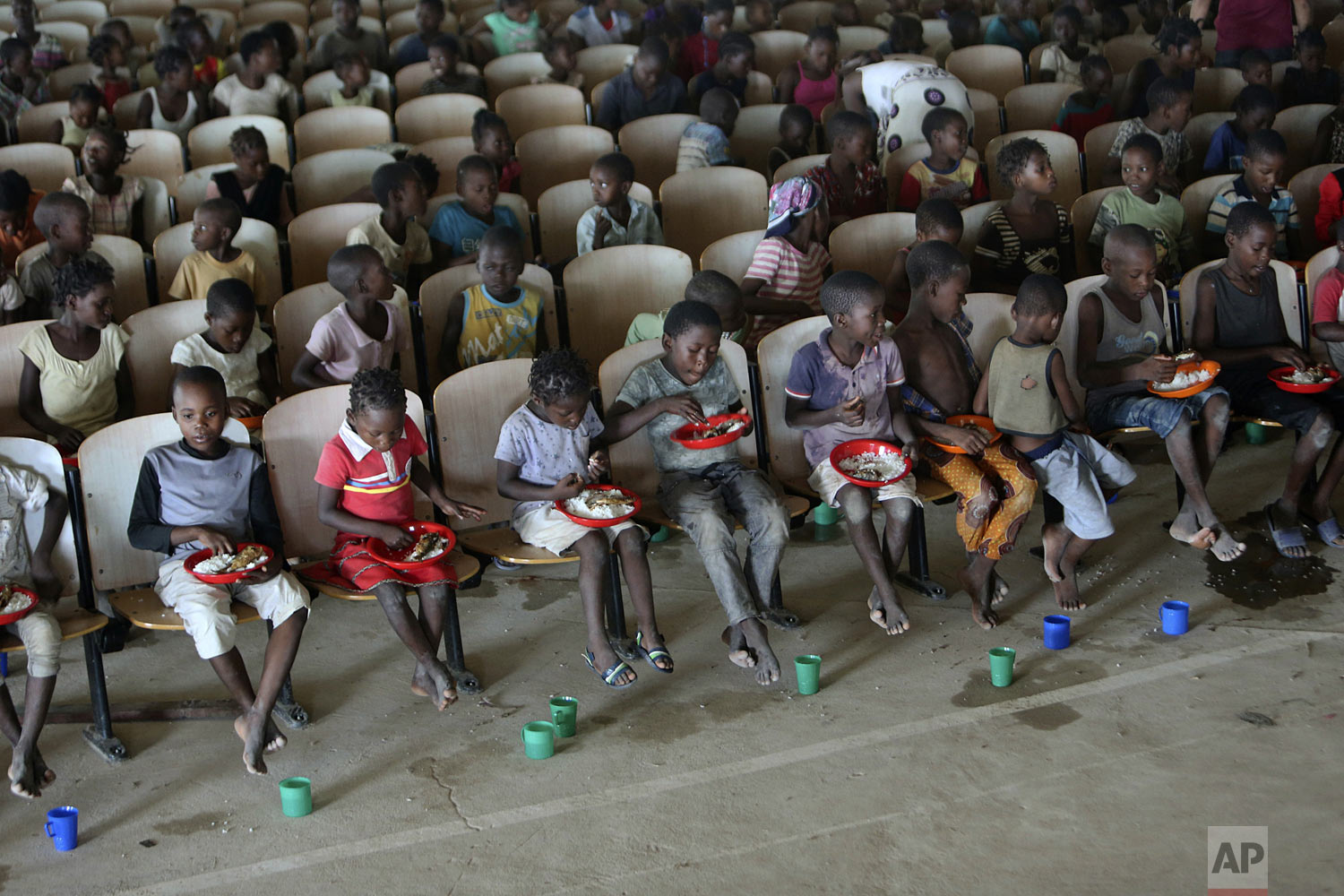 Children sit on benches in a hall after receiving food and drinking water at a temporary shelter for children in Pemba city, on the northeastern coast of Mozambique, Thursday May 2, 2019. More than 1 million children have been affected by a pair of 