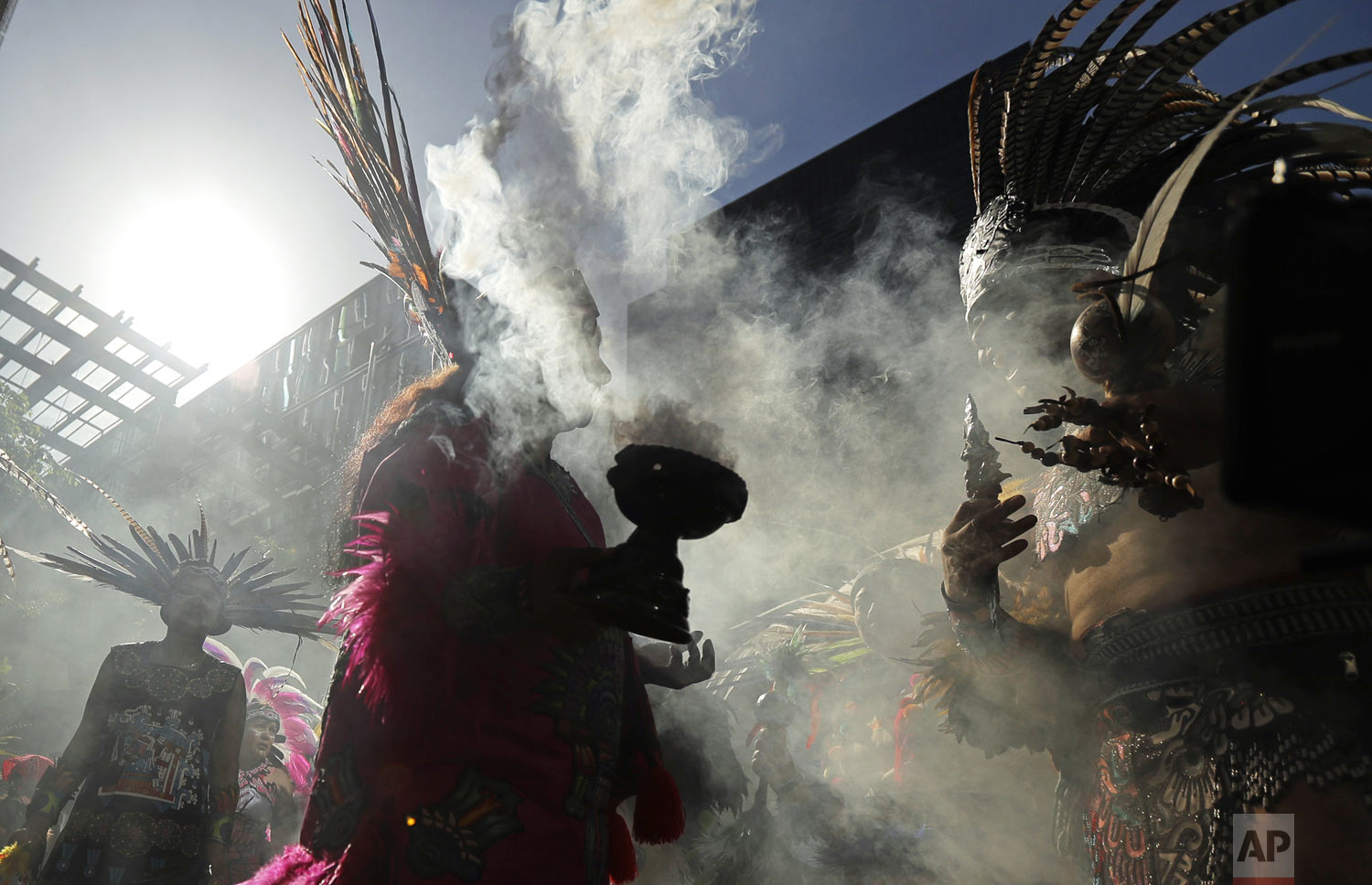 Smoke rises from a smudge pot as dancers with CeAtl Tonalli, a traditional Aztec Dance group, pause while taking part in a march for immigrant and workers rights, Wednesday, May 1, 2019, on May Day in downtown Seattle. (AP Photo/Ted S. Warren) 