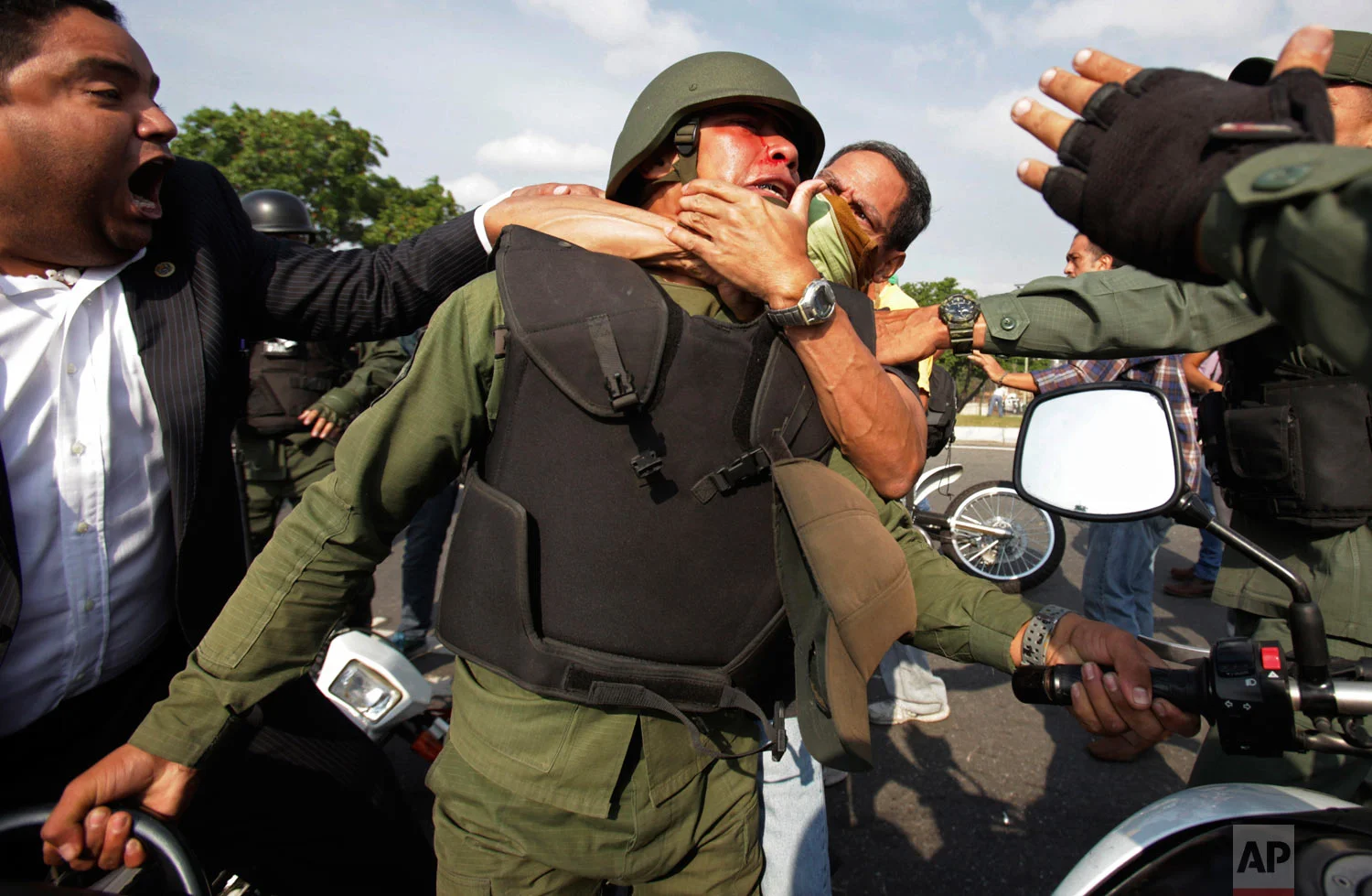 Opponents to Venezuela's President Nicolas Maduro, behind and left, scuffle with a National Guard who is loyal to President Nicolas Maduro during clashes with rebel soldiers attempting a military uprising outside La Carlota military airbase in Caracas, Venezuela, April 30, 2019. (AP Photo/Boris Vergara)