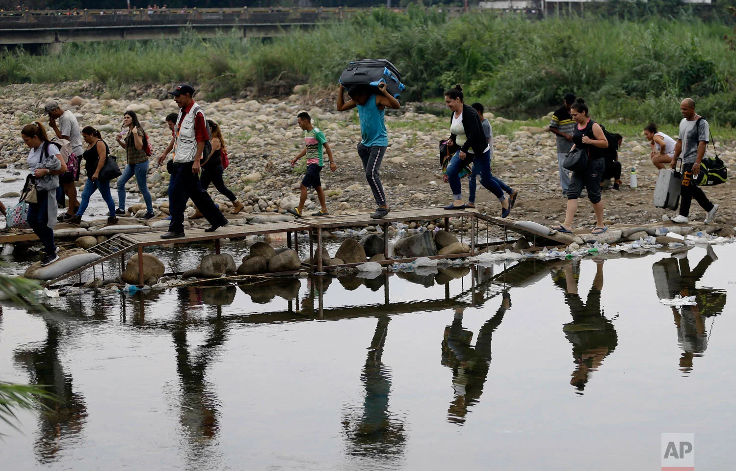 Venezuelans cross illegally into Colombia near the Simon Bolivar International Bridge, behind, top left, which is partially closed by Venezuelan authorities who are only permitting students, seniors and the sick to cross, seen from La Parada near Cucuta, Colombia, April 14, 2019. U.S. (AP Photo/Fernando Vergara)