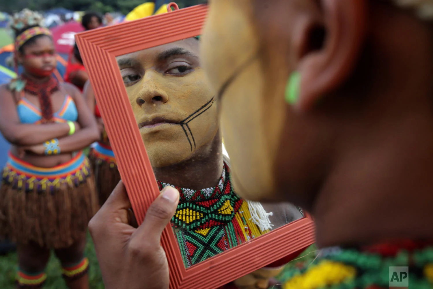 An indigenous man applies body paint during an annual campout protest for indigenous rights known as the Free Land Encampment in Brasilia, Brazil, April 24, 2019. (AP Photo/Eraldo Peres)