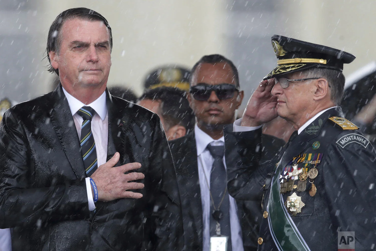 Brazil's President Jair Bolsonaro puts his hand over his heart as Army Commander Edson Leal Pujol salutes during the playing of the national anthem during a ceremony marking Army Day, in Brasilia, Brazil, April 17, 2019. (AP Photo/Eraldo Peres)