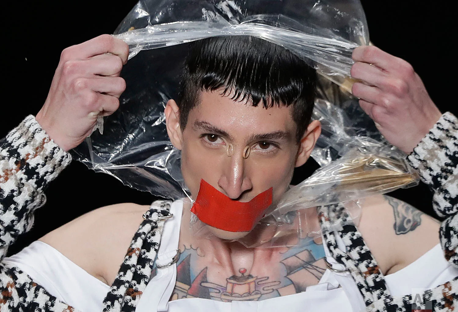 A model tears a plastic bag from his head, as he wears a creation from the João Pimenta collection during Sao Paulo Fashion Week in Sao Paulo, Brazil, April 24, 2019. (AP Photo/Andre Penner)