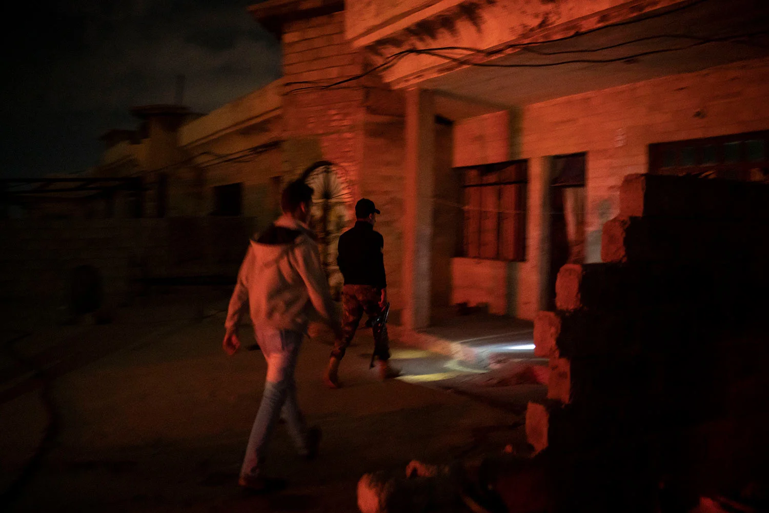 In this April 2, 2019 photo, an Iraqi army 20th division soldier walks with a civilian during a nighttime raid near Badoush, Iraq. (AP Photo/Felipe