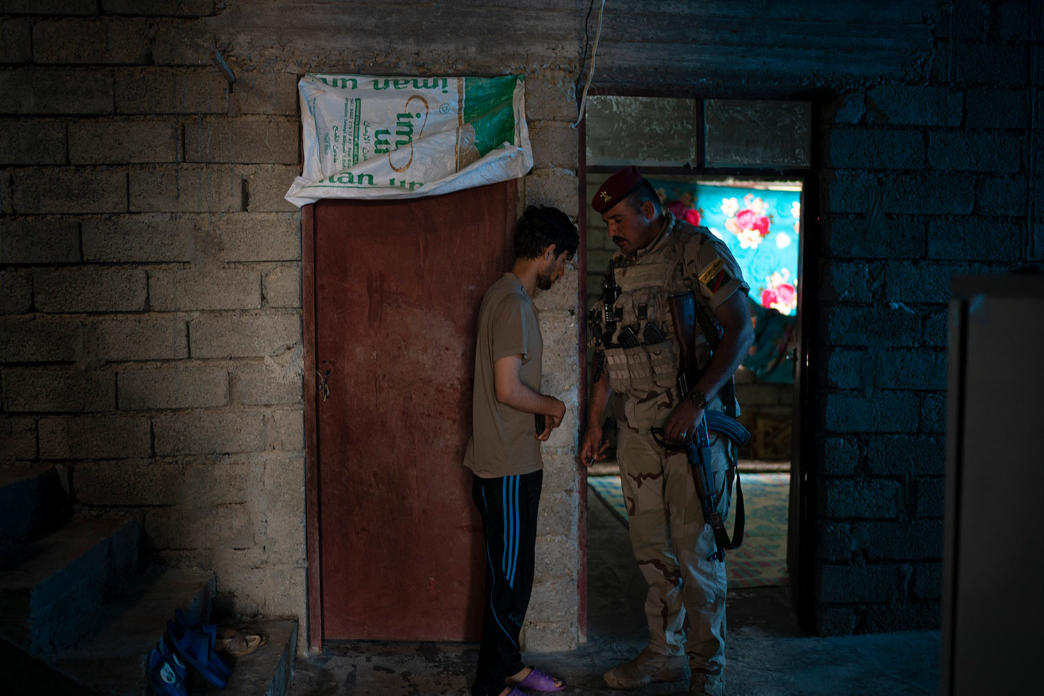 In this April 5, 2019 photo, an Iraqi army 20th division soldier talks to a suspect as they search his house during a raid in Badoush, Iraq. He taken into custody and then released after he was able to prove his whereabouts during IS rule. (AP Photo/Felipe Dana)