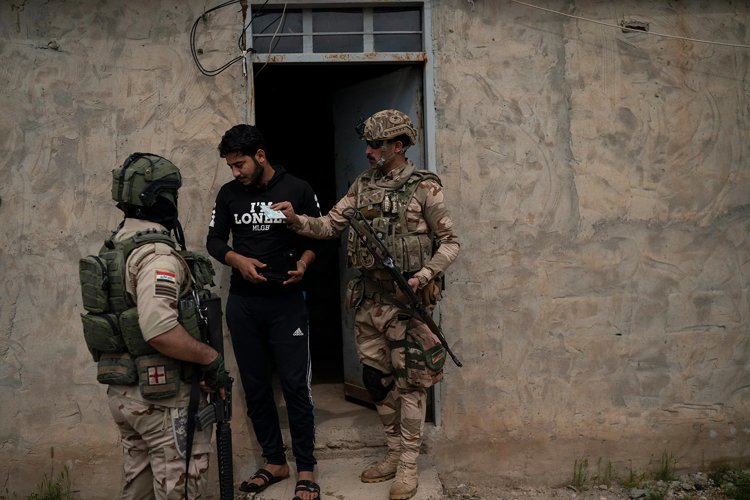 In this April 5, 2019 photo, Iraqi army 20th division soldiers check the ID of a man during a raid in Badoush, Iraq. (AP Photo/Felipe Dana)