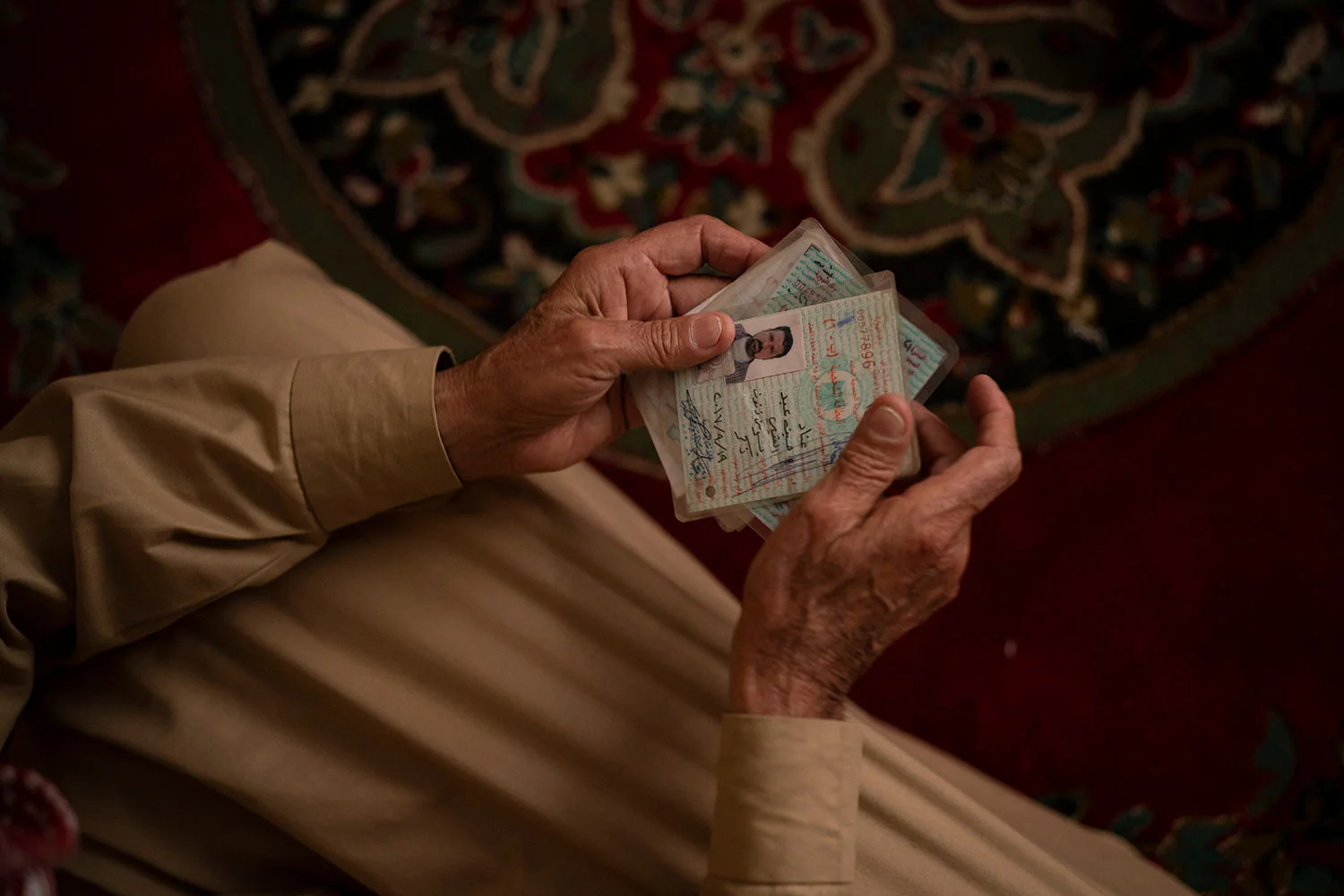 In this April 14, 2019 photo, Hussein Abd holds the ID's of his three dead sons as he sits in his house during an interview in Mosul, Iraq. They were killed in their home in Badoush by Islamic State militants in a chilling attack last January. (AP Photo/Felipe Dana)
