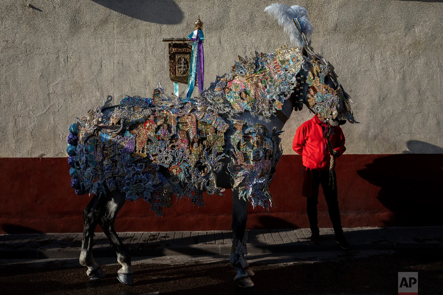 A horse and entrant of "Los Caballos del Vino," usually translated as the Running of the Wine Horses, wait in downtown for the start of the competition in Caravaca de la Cruz, southeast Spain, Thursday, May 2, 2019. (AP Photo/Bernat Armangue)