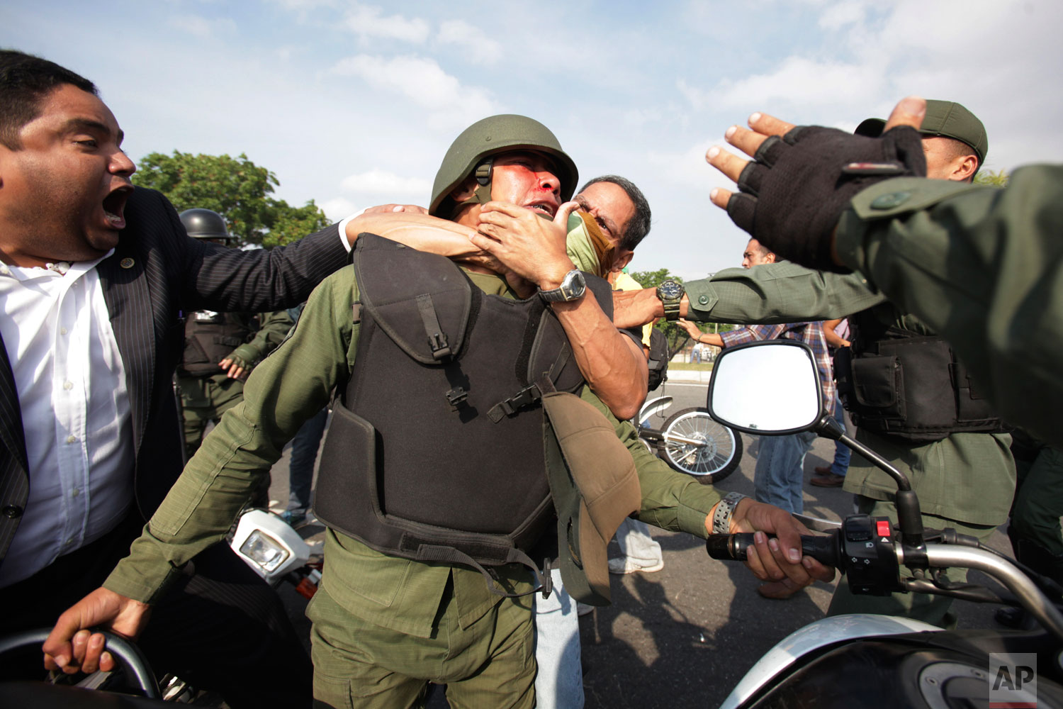 Opponents to Venezuela's President Nicolas Maduro, behind and left, scuffle with a National Guard who is loyal to President Nicolas Maduro during clashes with rebel soldiers attempting a military uprising outside La Carlota military airbase in Caracas, Venezuela, Tuesday, April 30, 2019. (AP Photo/Boris Vergara)