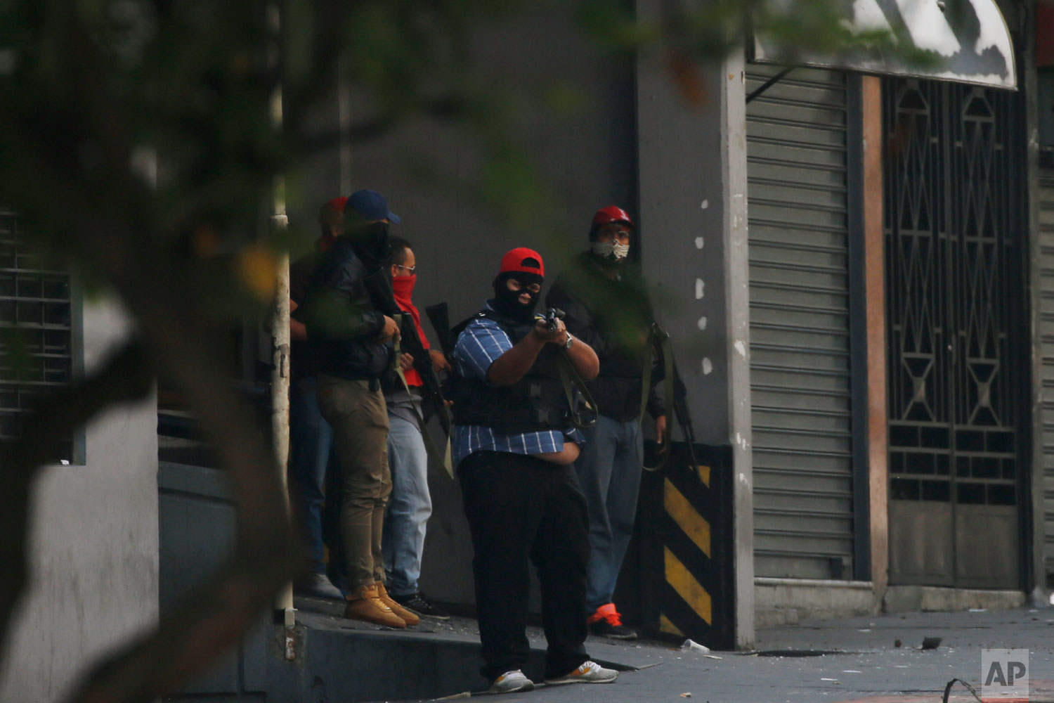 Armed and masked supporters of President Nicolas Maduro stand at an entrance of the Transportation Ministry in Caracas, Venezuela, Tuesday, April 30, 2019, during a failed military uprising attempt to oust Maduro. (AP Photo/Fernando Llano)