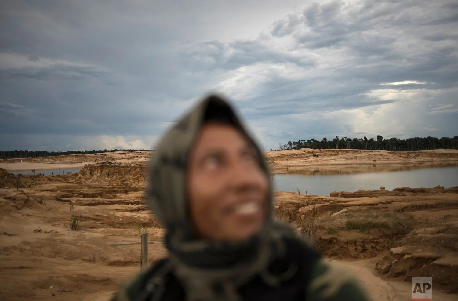 A police officer smiles while riding in a pick-up truck, April 3, 2019, during a patrol in Peru’s Tambopata province. The area known by miners as "La Pampa," which surrounds a national park and doesn't appear on state maps, has yielded roughly 25 tons of illegally mined gold a year, much more than the legally produced amount in the same area, according to the Peruvian government. (AP Photo/Rodrigo Abd)