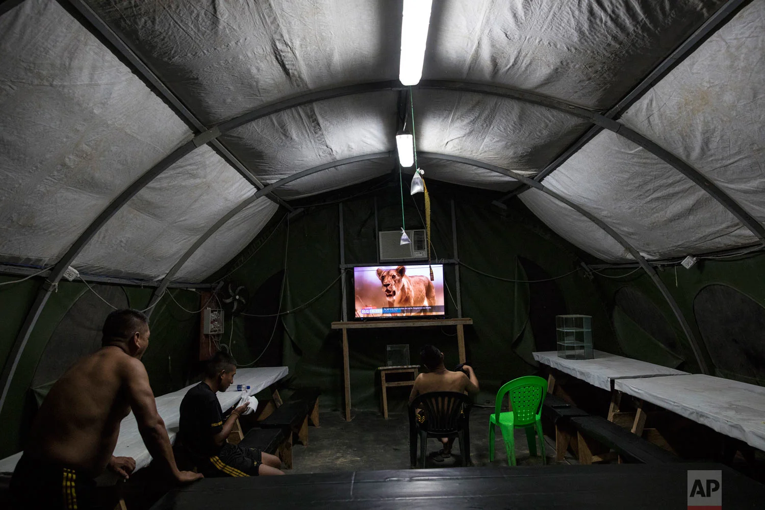 Soldiers watch a nature show in their tent at the Balata military and police base, March 31, 2019, in Peru’s Tambopata province. The base is surrounded by two lakes contaminated with mercury, as well as debris left over by miners. (AP Photo/Rodrigo Abd)