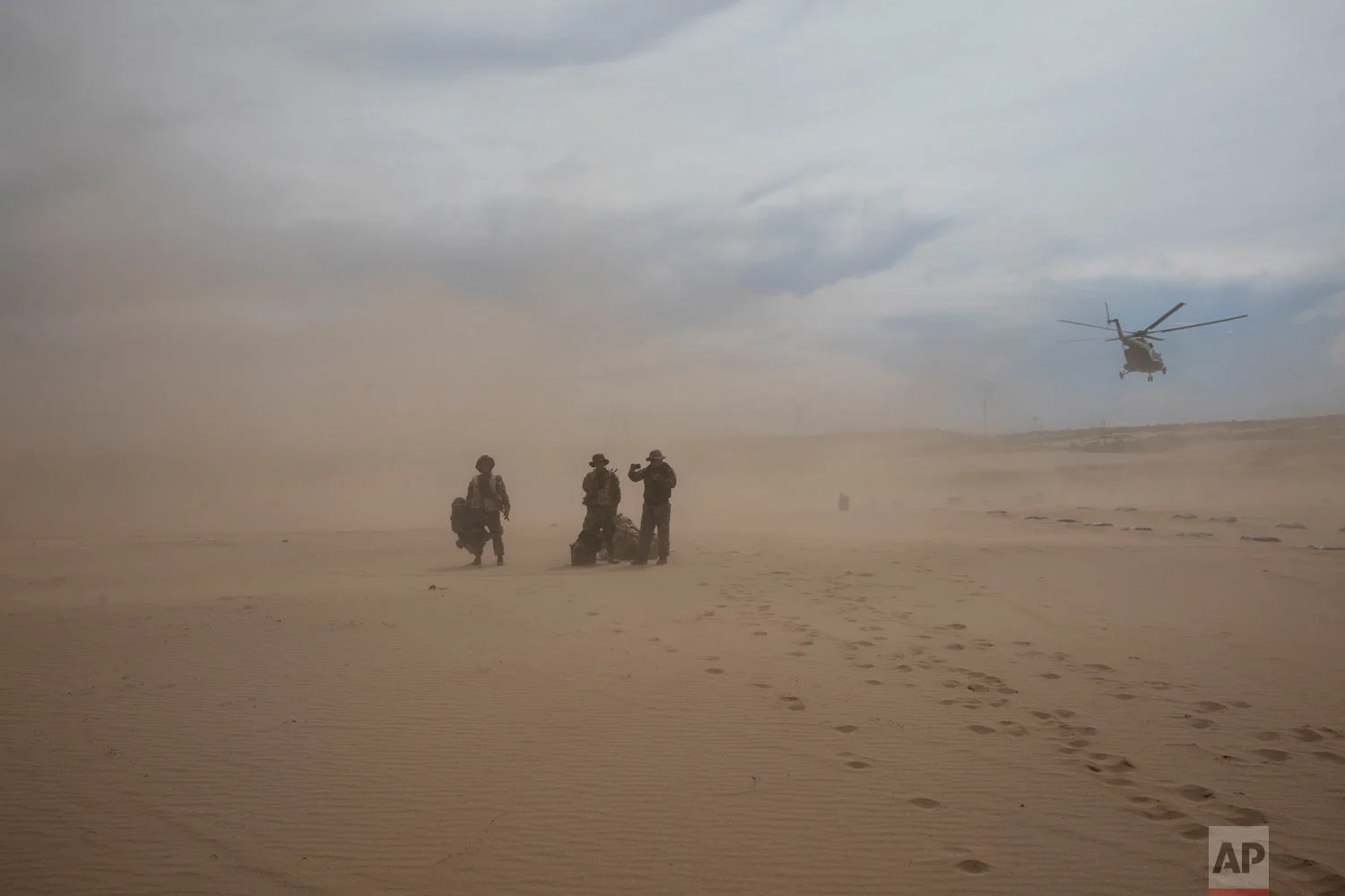 "Operation Mercury" soldiers arrive for their new assignment stand in a dust cloud on a makeshift airstrip on April 1, 2019, at the Balata police and military base in Peru's Tambopata province, as the helicopter that brought them returns to the home base. (AP Photo/Rodrigo Abd)