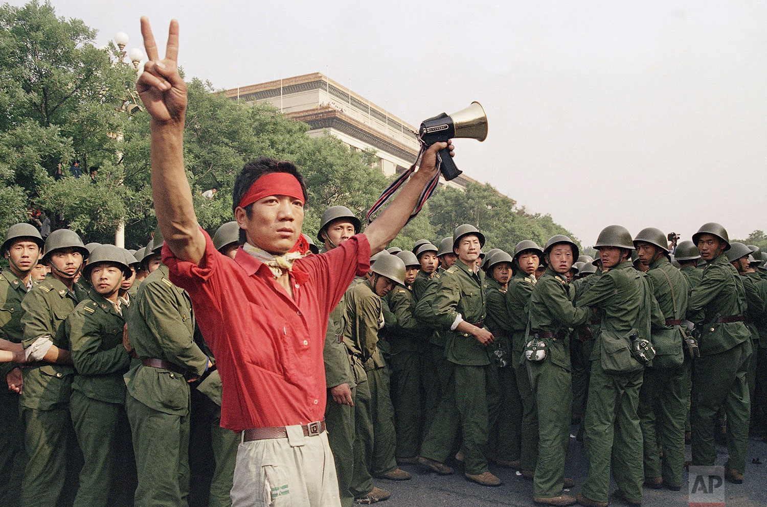  A student pro-democracy protester flashes victory signs to the crowd as People's Liberation Army troops withdraw on the west side of the Great Hall of the People near Tiananmen Square on Saturday, June 3, 1989 in Beijing. (AP Photo/Mark Avery) 