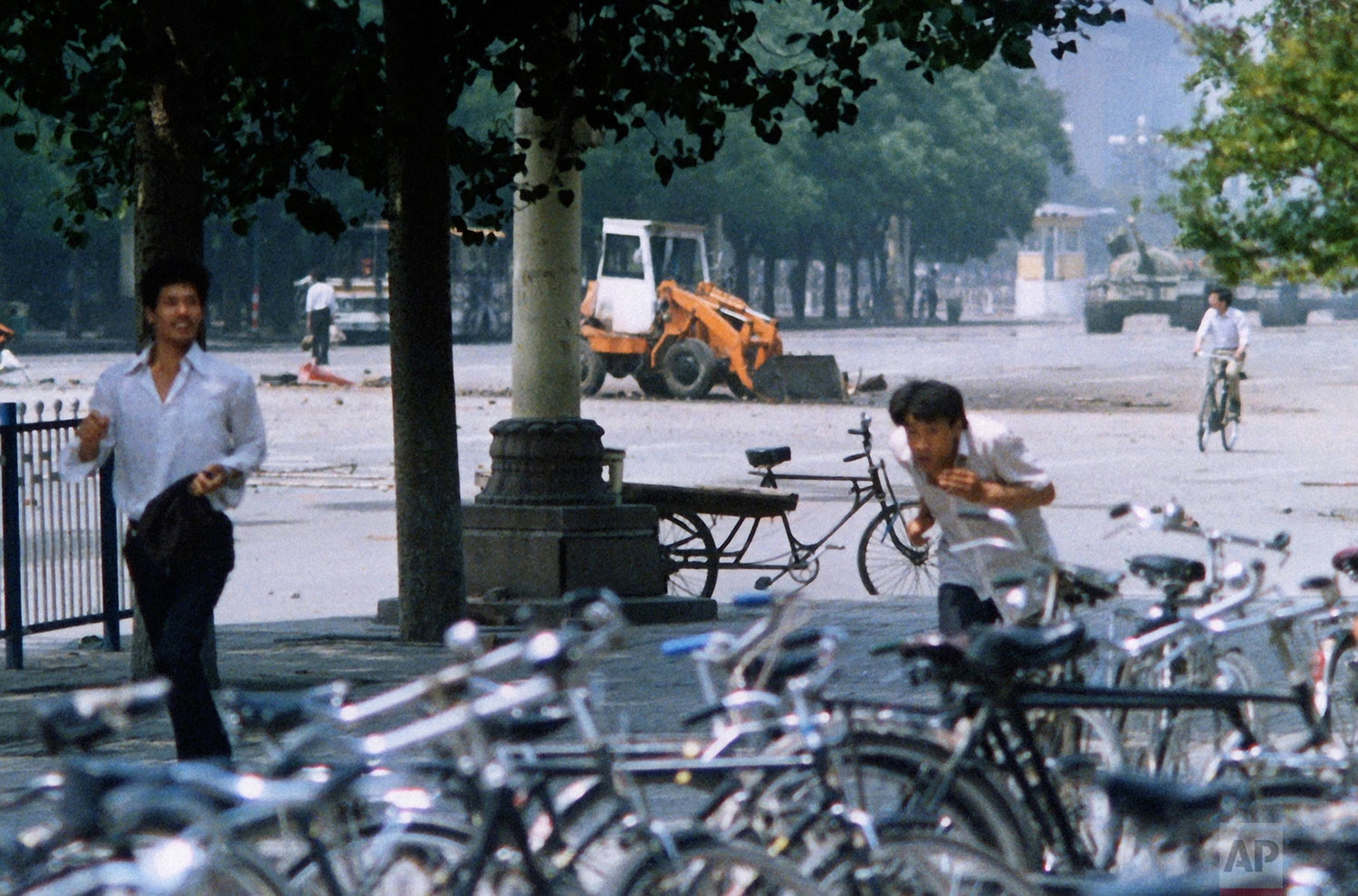  In this photo taken on June 5, 1989 and made available for the first time by the AP on Thursday June 4, 2009, three unidentified men flee the scene, as a Chinese man, background left, stands alone to block a line of approaching tanks, background rig