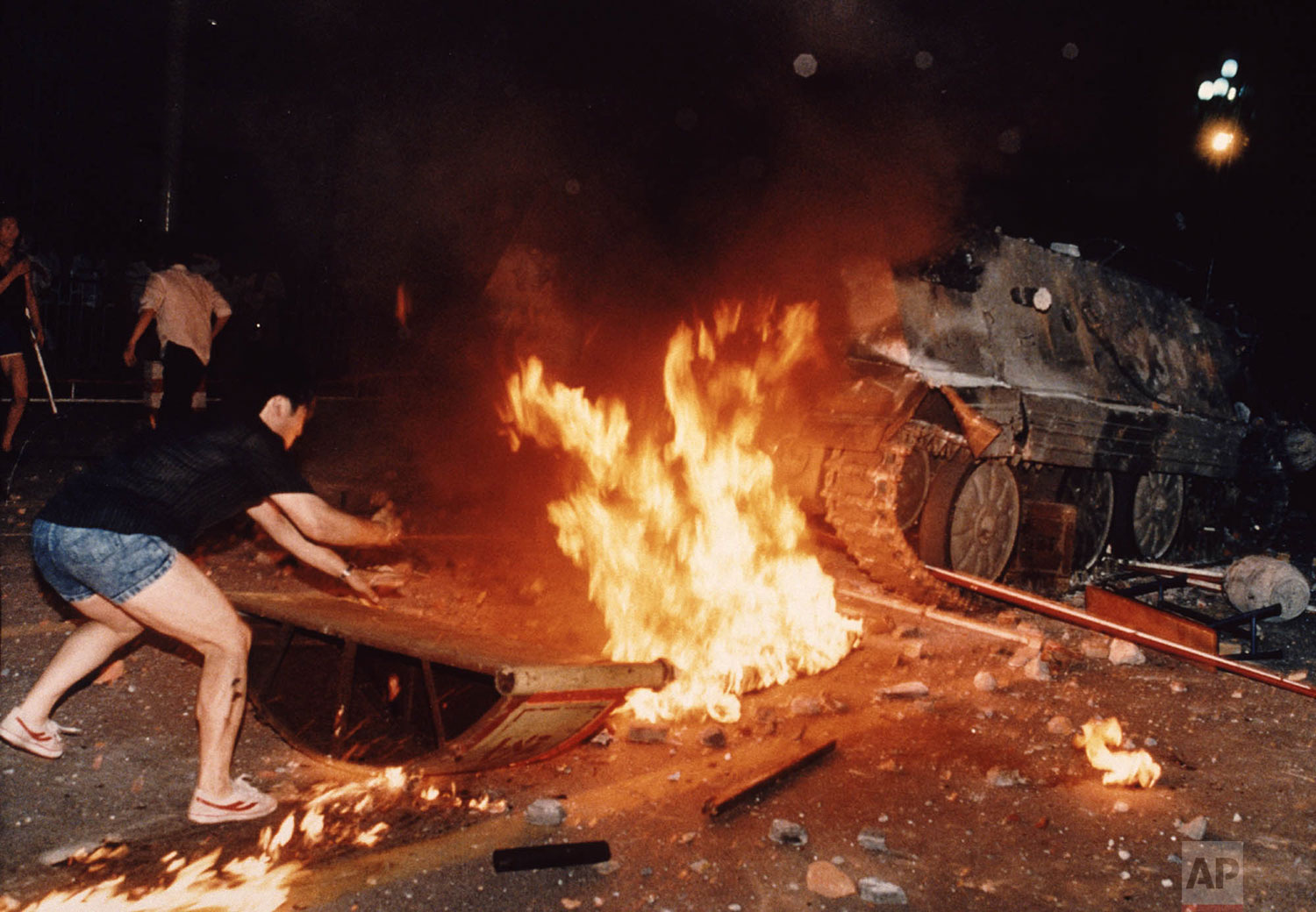  A student protester puts barricades in the path of an already burning armored personnel carrier that rammed through student lines during an army attack on anti-government demonstrators in Beijing's Tiananmen Square, early June 4, 1989. A government 