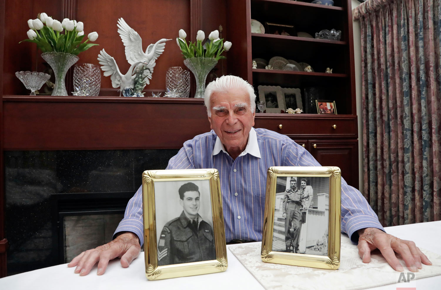 In this photo taken May 20, 2019, veteran Norman Harold Kirby sits with a photo of his mother, Katherine Louise Kirby, and himself, at 17, and a post-war portrait as he poses for a photo at his home in Lions Bay, Canada. The Canadian from British Columbia had joined the army when he was only 17 and was barely a 19-year-old private when he climbed into the landing craft that would take him to shore on June 6, 1944. (AP Photo/Elaine Thompson)