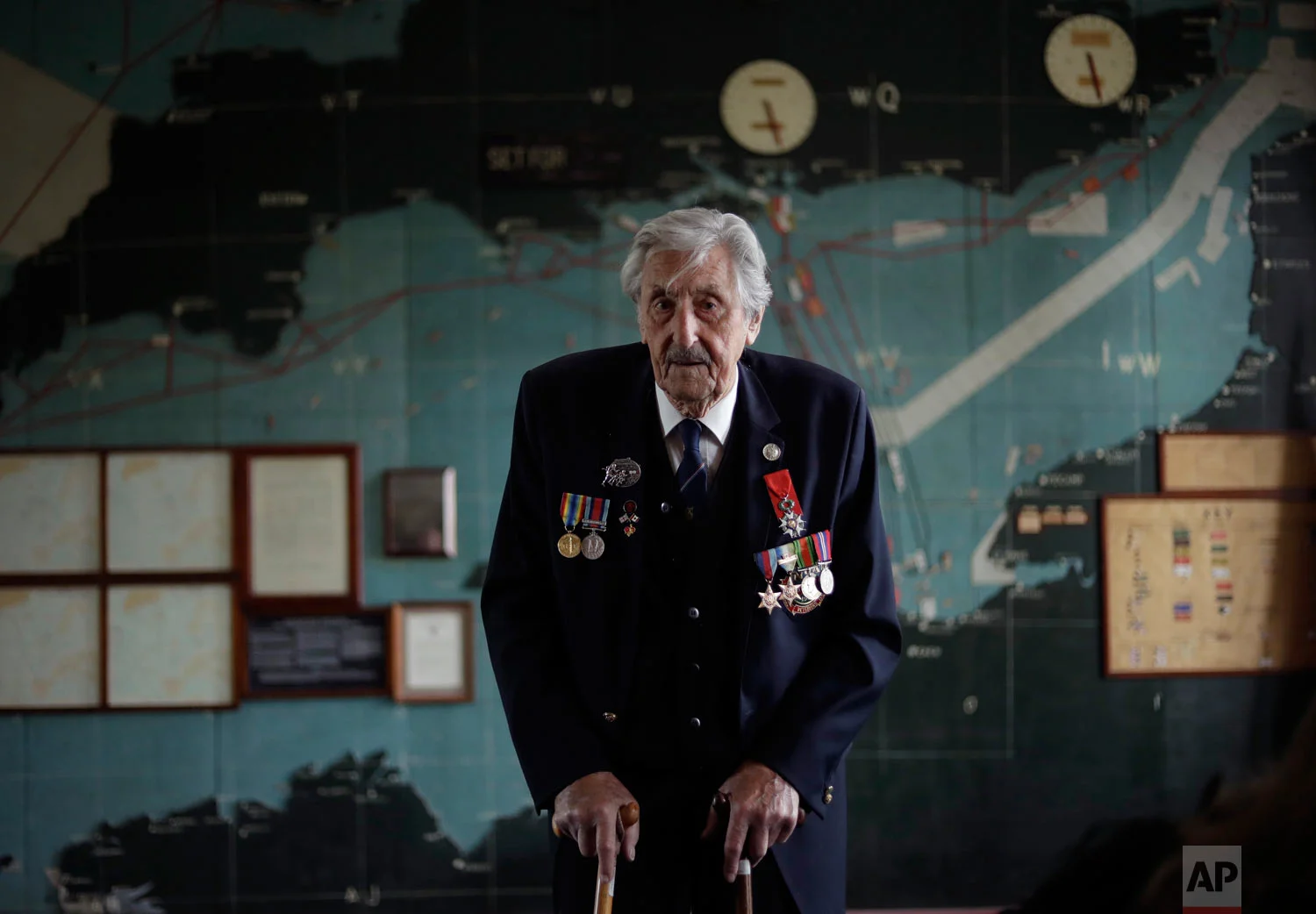 British D-Day veteran Leonard 'Ted' Emmings, who was a naval Coxswain serving on a small landing craft which landed 36 Canadians on Juno beach in France, poses for photographs backdropped by the map used to plan the Normandy D-Day landings at Southwick House near Portsmouth, England, May 9, 2019. Southwick House was the forward headquarters of the allied forces preparing for the invasion of Normandy in 1944, the nerve center of D-Day. (AP Photo/Matt Dunham)