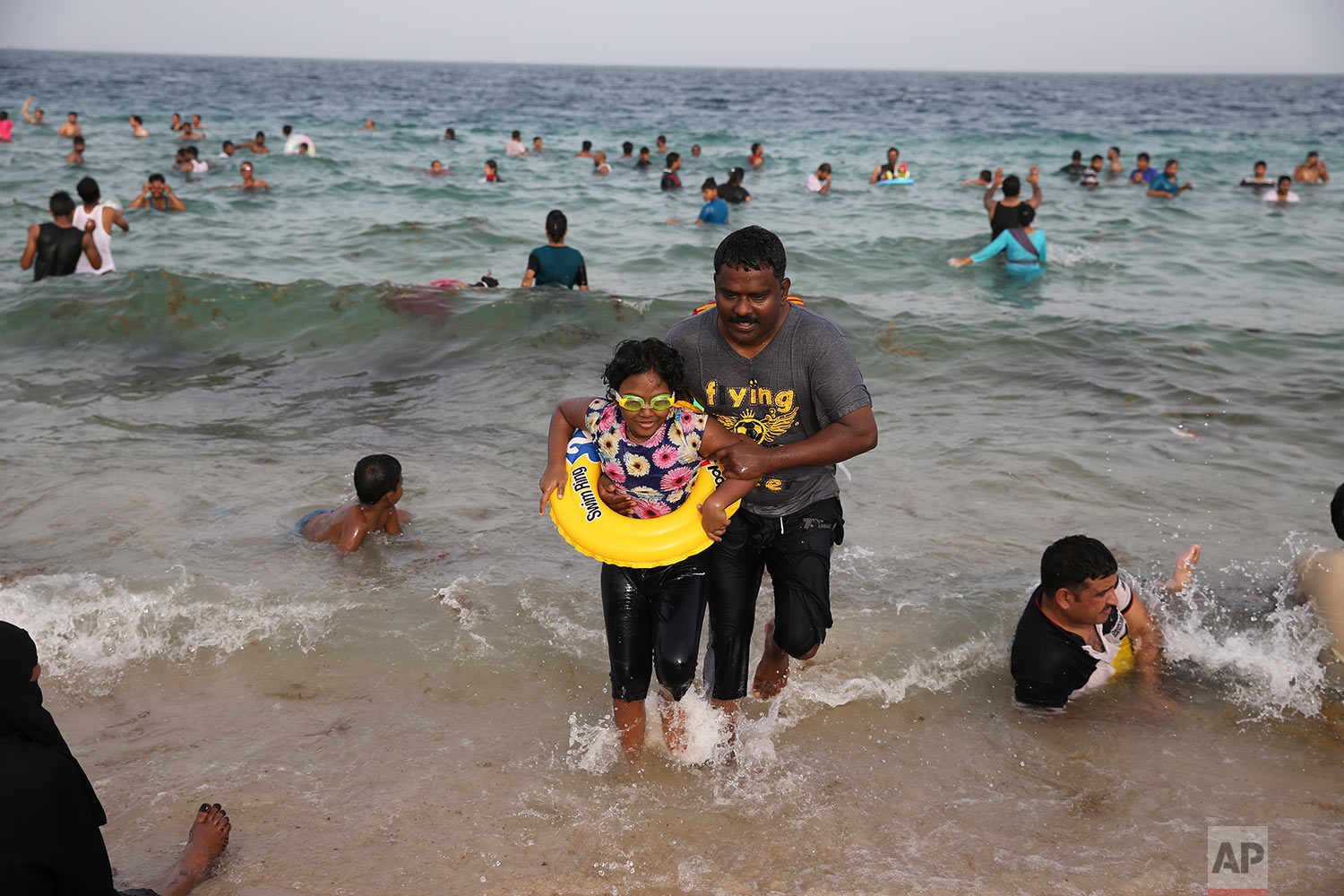  In this Friday, April 19, 2019 photo, a man helps a girl to get out of the water as the people enjoy swimming at the Sealine Beach about 40 kms, 25 miles, south of Doha, Qatar. (AP Photo/Kamran Jebreili) 