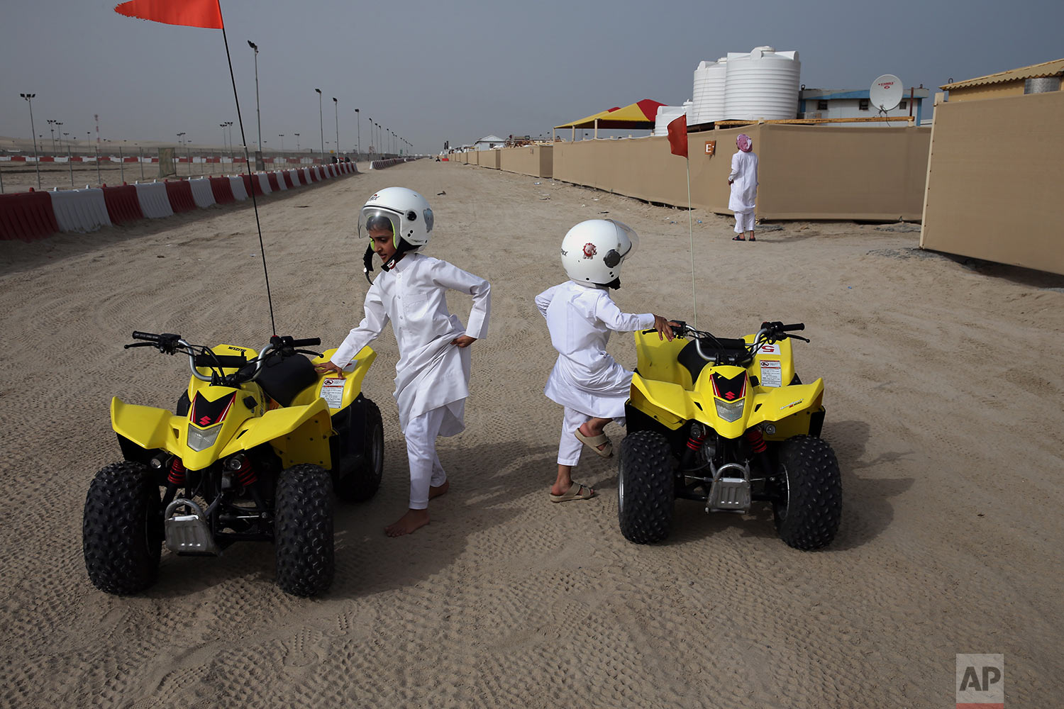  In this Friday, April 19, 2019 photo, two brothers get on their rental dune buggies at a camp by the sealine road, about 40 kms, 25 miles, south of Doha, Qatar. (AP Photo/Kamran Jebreili) 