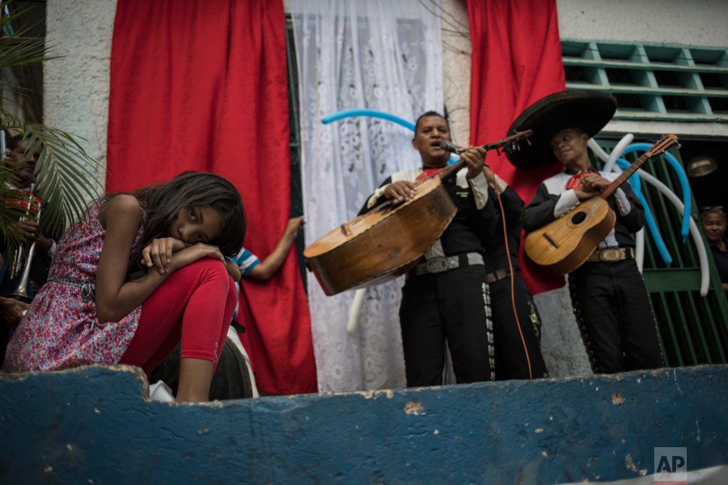 A girl lays her head down as she listens to mariachi musicians performing during a Mother's Day block party in Caracas, Venezuela, late Sunday, May 19, 2019. (AP Photo/Rodrigo Abd)