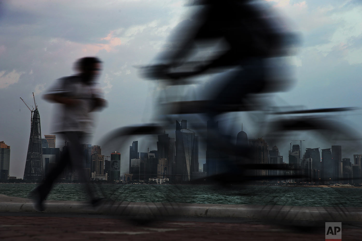  In this Sunday, Feb. 17, 2019 photo, people pass by the city skyline during their early morning workout in Doha, Qatar. (AP Photo/Kamran Jebreili) 