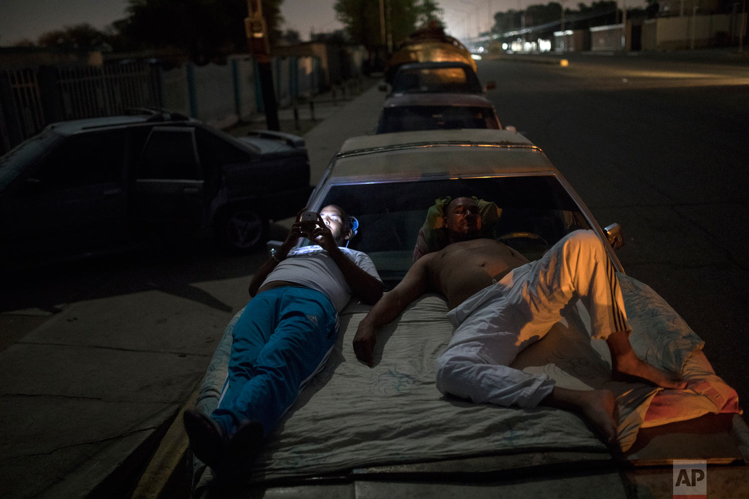  Andres Quintero, left, and Fermin Perez rest on top of Perez's car as they wait in line for over 20 hours to fill their tanks with gas in Cabimas, Venezuela, Thursday, May 16, 2019. U.S. sanctions on oil-rich Venezuela resulyrf in mile-long lines fo