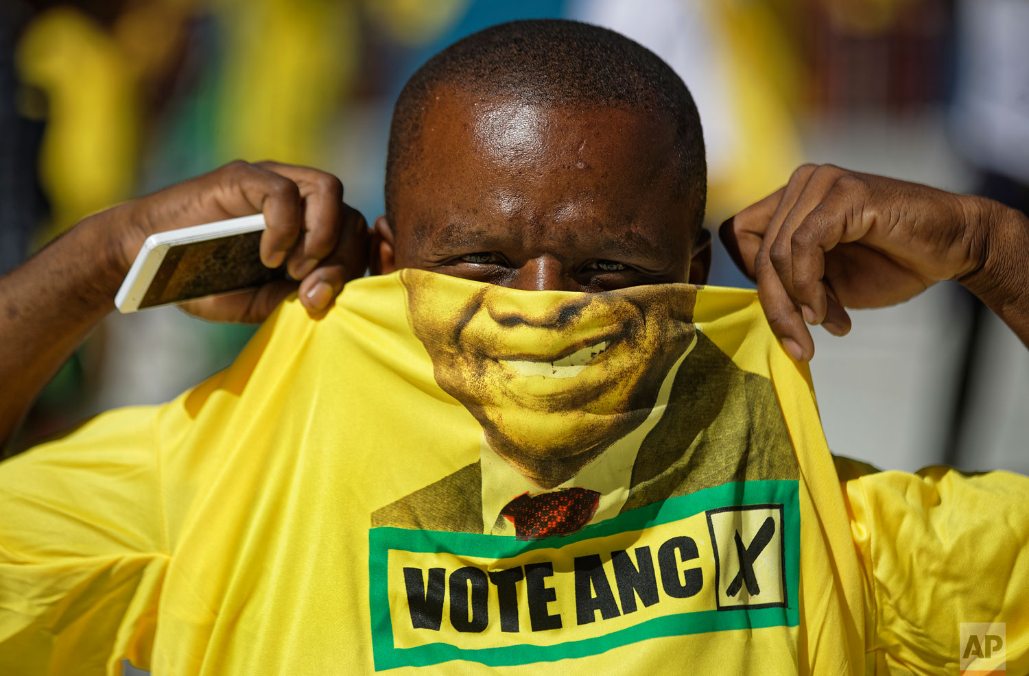 A supporter of the ruling African National Congress (ANC) holds up a t-shirt of President Cyril Ramaphosa as he attends their final election rally at Ellis Park stadium in Johannesburg, South Africa Sunday, May 5, 2019. (AP Photo/Ben Curtis)