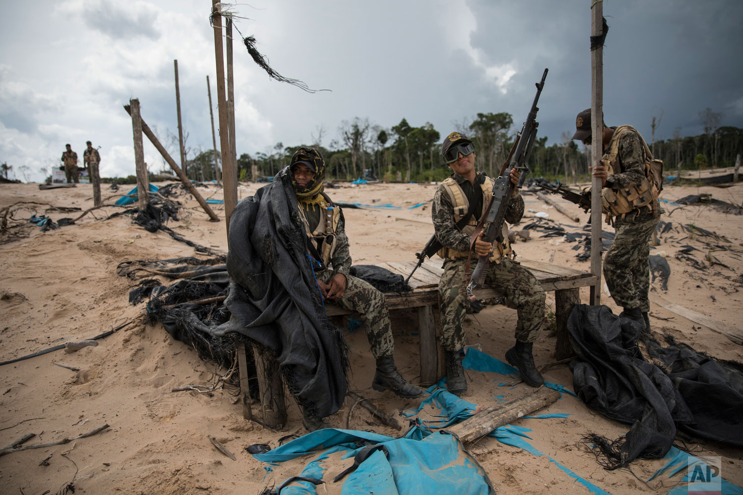 In this April 1, 2019 photo published May 15, soldiers wait for the arrival of a helicopter bringing supplies and replacements, on a makeshift airstrip of the Balata police and military base in Peru's Tambopata province. Peru has installed military bases in the province in hopes of curbing not just illegal mining but also human trafficking and other associated crimes. (AP Photo/Rodrigo Abd)