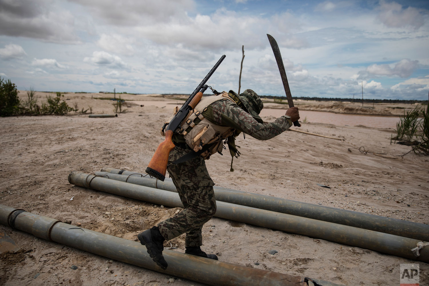 In this March 27, 2019 photo published May 15, a soldier hacks with a machete tubing used by illegal miners to mine gold, as part of "Operation Mercury", in Peru’s Tambopata province. The police and soldiers occasionally find machinery used by the illegal miners, and blow it up with dynamite. They also destroy metal tubing used to mine gold. (AP Photo/Rodrigo Abd)