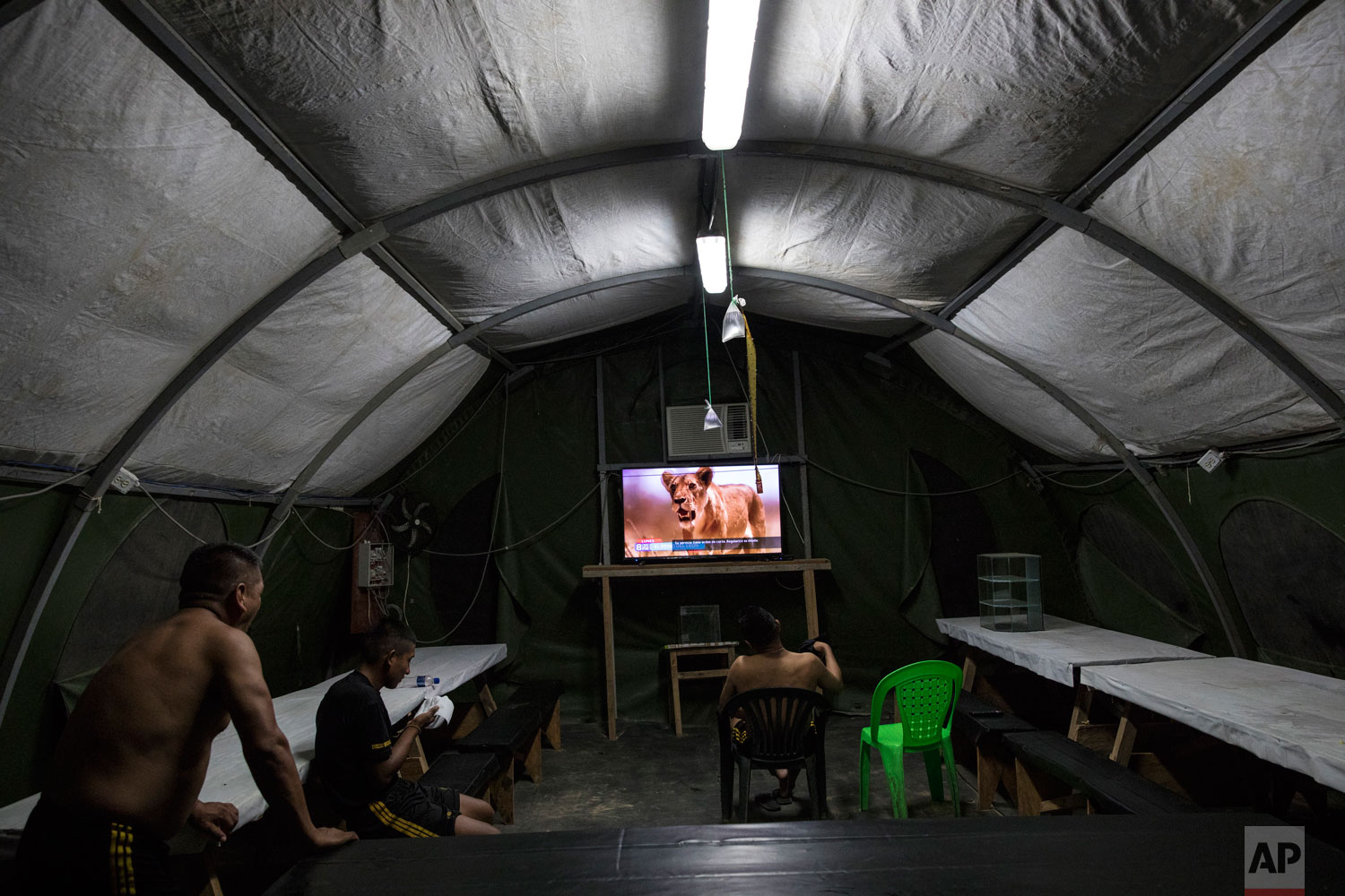 In this March 31, 2019 photo published May 15, soldiers watch a nature show in their tent at the Balata military and police base in Peru’s Tambopata province. The military bases will remain at least through mid-2021, when the term of the current government ends.(AP Photo/Rodrigo Abd)