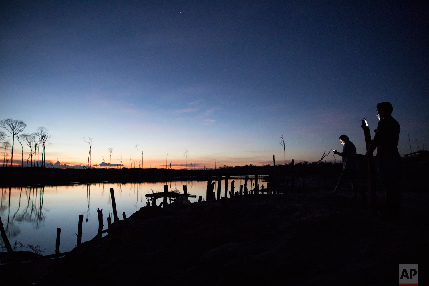 In this March 31, 2019 photo published May 15, police officers call home from their remote outpost outside the Balata military and police base in Peru's Tambopata province. The base, once an illegal gold mining camp, is occupied by "Operation Mercury" security forces and is surrounded by two lakes contaminated with mercury, as well as debris left over by miners. (AP Photo/Rodrigo Abd)