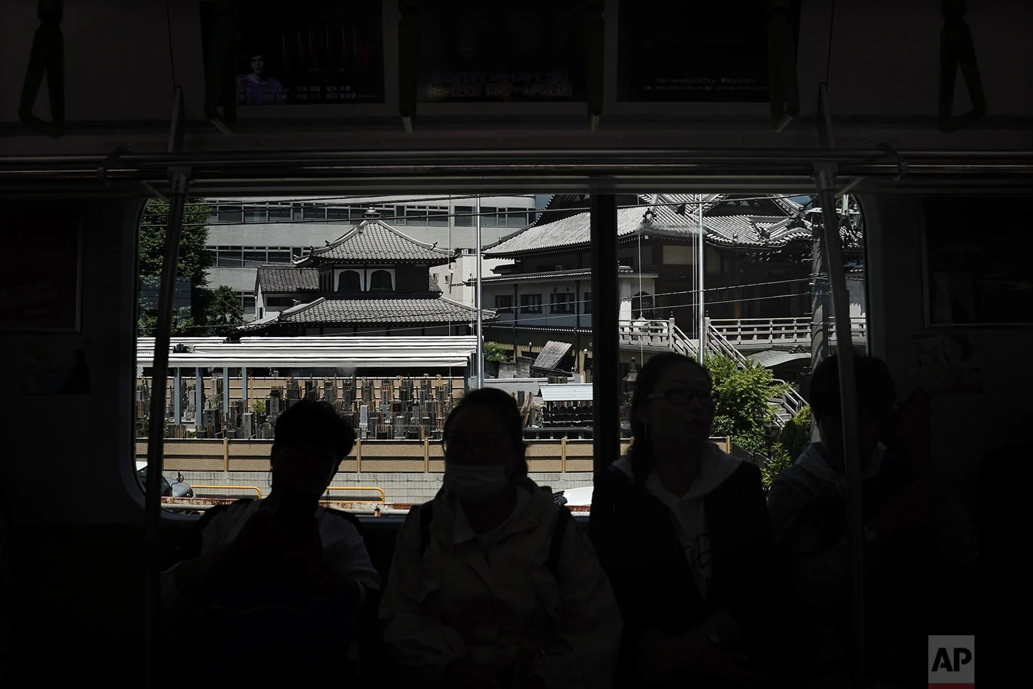 A group of tourists are silhouetted in a Yamanote Line train as a Buddhist temple is seen through a window near Hamamatsucho Station in Tokyo, Wednesday, May 22, 2019. (AP Photo/Jae C. Hong)