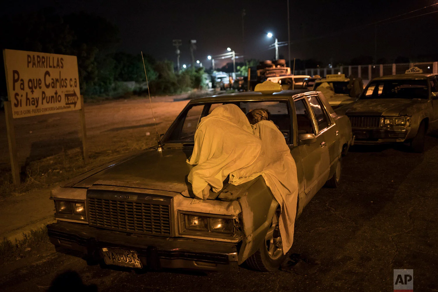 A man sleeps on top of his car as he waits in line to fill up outside a gas station in Maracaibo, Venezuela, May 23, 2019. (AP Photo/Rodrigo Abd)
