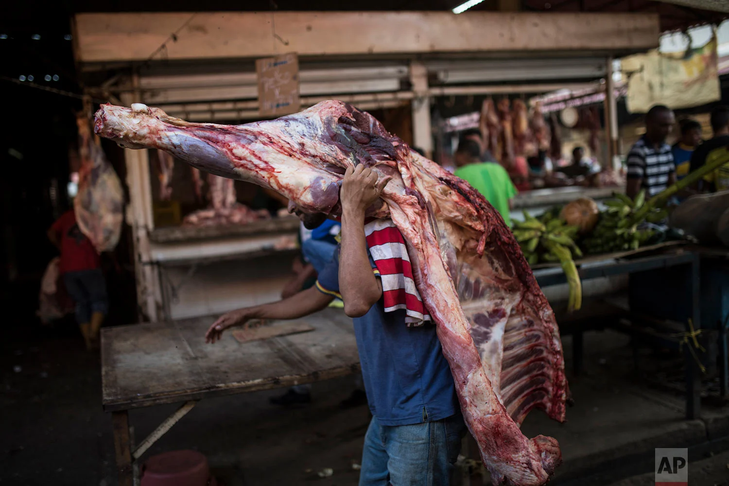 A vendor carries beef to a butcher shop at the flea market in Maracaibo, Venezuela, May 16, 2019. He'll have to sell it quickly, since perishables go bad quickly without refrigeration in Maracaibo's suffocating temperatures. (AP Photo/Rodrigo Abd)