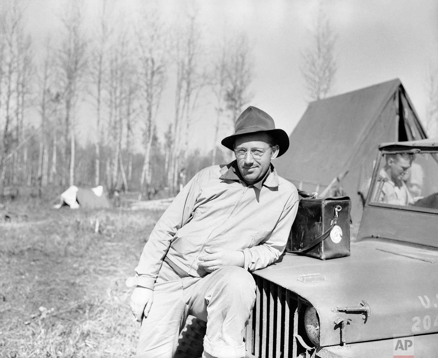Grant MacDonald, Wide World photographer, unshaven, very dirty, and slightly unhappy about it all, rests in the dust and mosquitoes, after reaching the end of the line, last outpost of construction crews on the Alaska road between Fort St. John and Fort Nelson, June 6, 1942. (AP Photo)