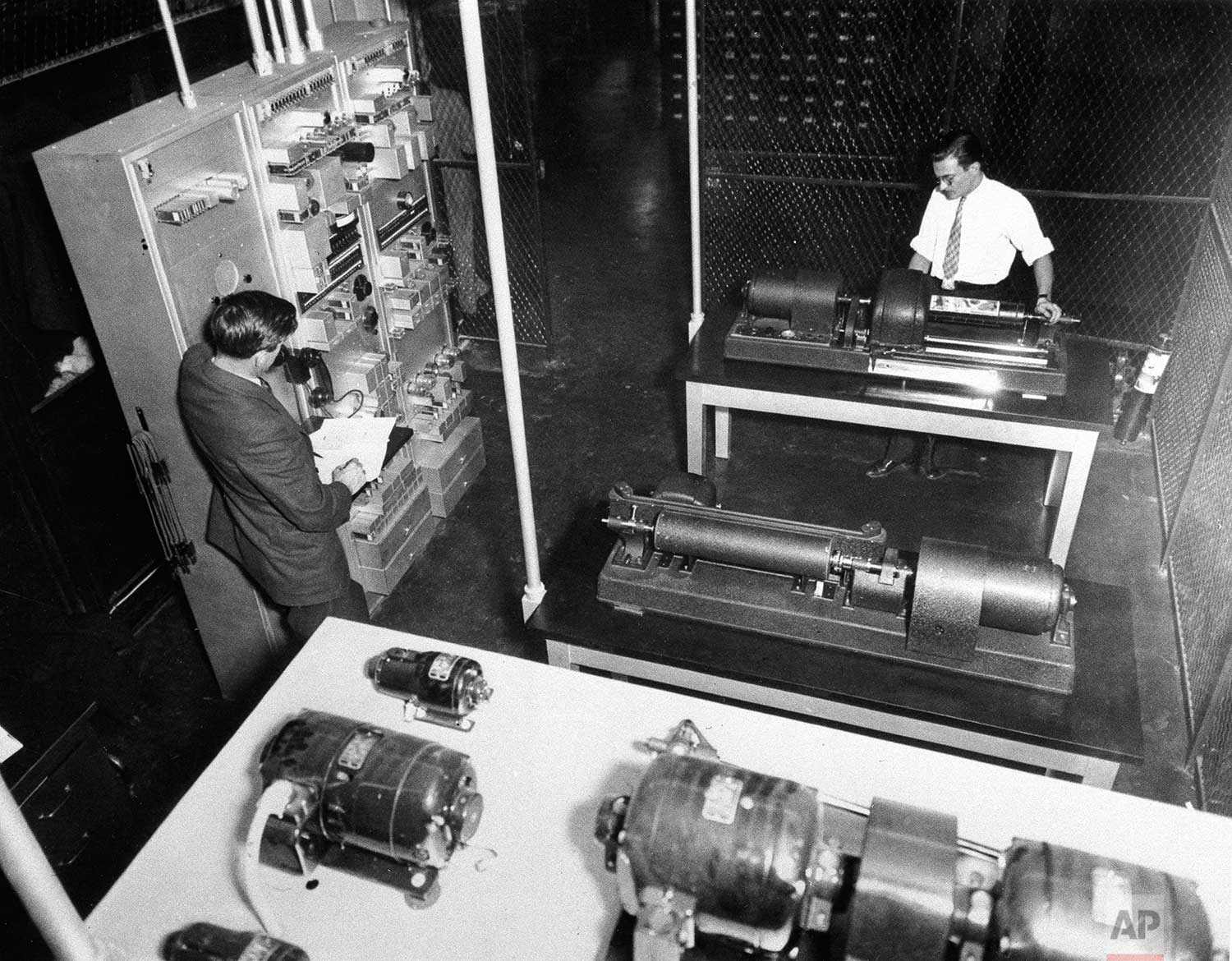 A wire photo receiver showing the cylinder in which the negative is contained, is shown in The Associated Press' photo department in New York, 1935, with Eddie Nittoly, right, attending to the machine. (AP Photo)