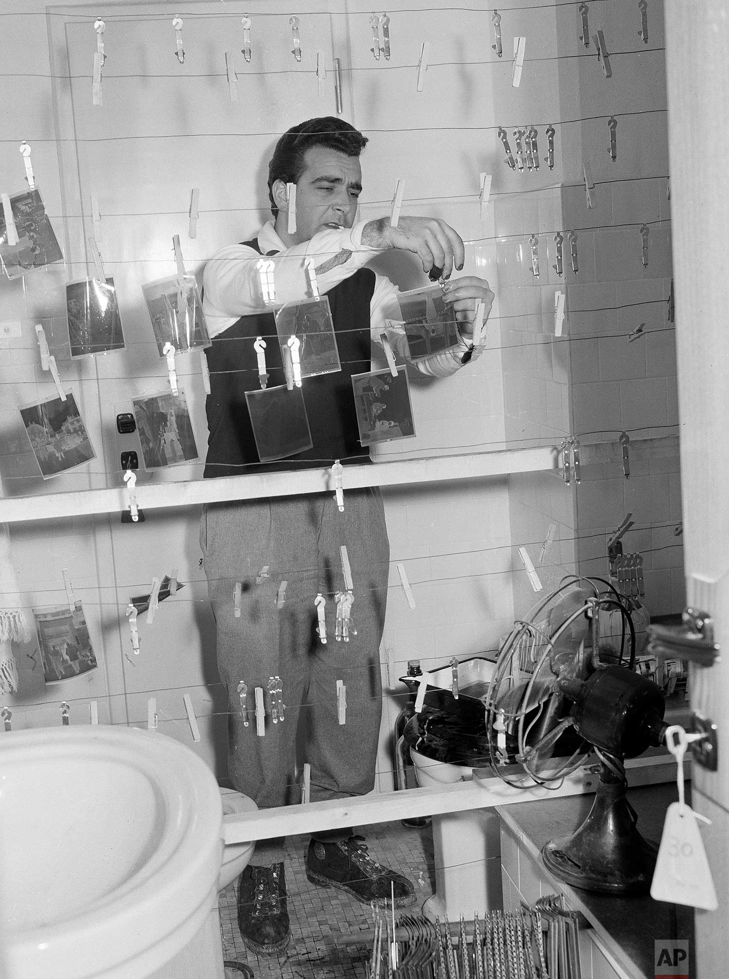 Rome darkroom staffer Carlo Pelliccia dries negatives in a bathroom where film for five AP photographers was being processed during the 1956 Winter Olympics in Cortina, Italy. (AP Photo/Walter Attenni)