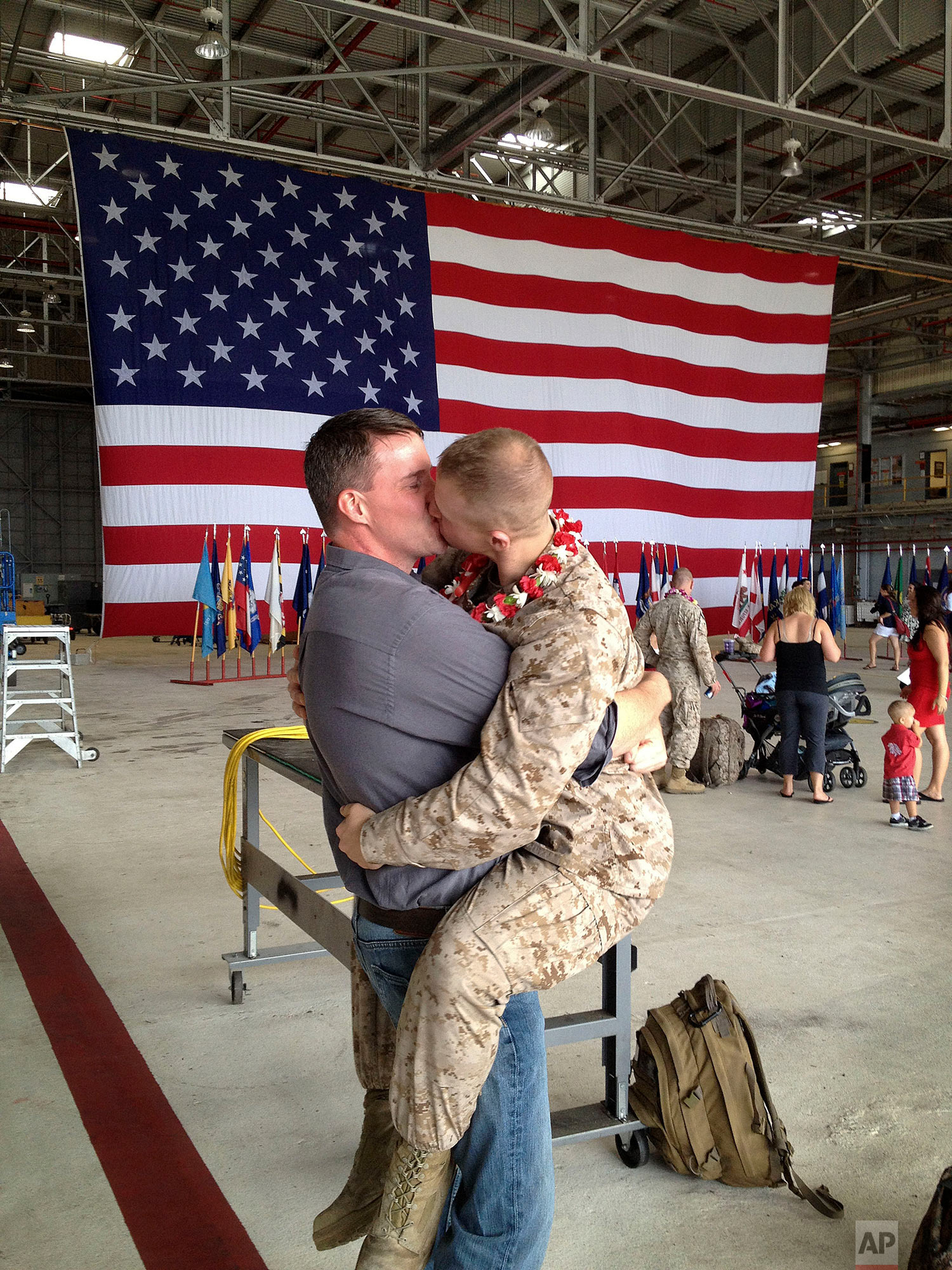 In this Wednesday, Feb. 22, 2012 file photo, Sgt. Brandon Morgan, right, kisses his partner, Dalan Wells, in a helicopter hangar at the Marine base in Kaneohe Bay, Hawaii upon returning from a six-month deployment to Afghanistan. The photo, made some five months after the repeal of the military's "don't ask don't tell" policy prohibiting gay servicemen from openly acknowledging their sexuality, was among the first showing a gay active duty serviceman in uniform kissing his partner at a homecoming. (AP Photo/David Lewis)