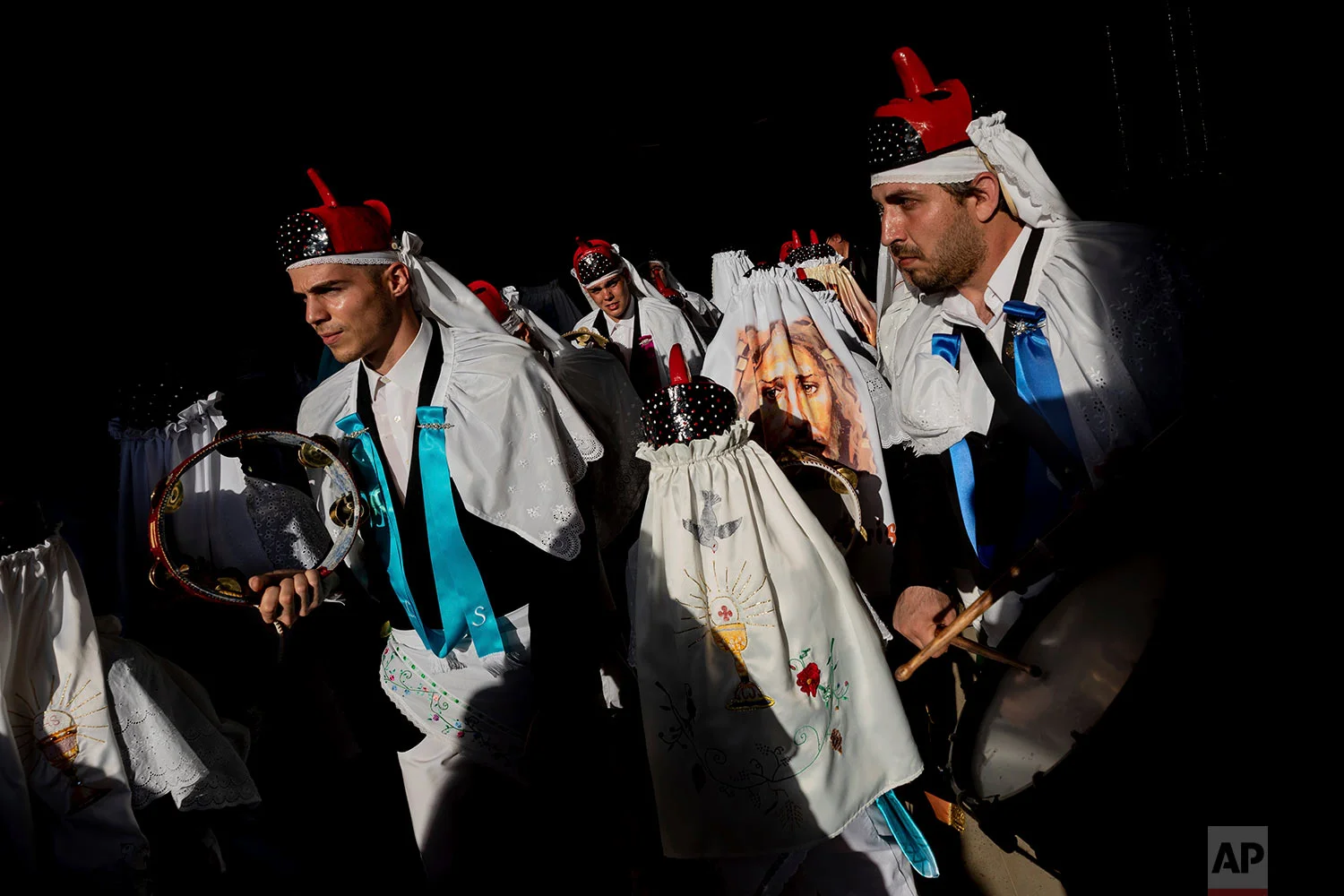 In this Thursday, June 20, 2019 photo, members of the "Hermandad del santísimo sacramento pecados y danzantes" brotherhood representing the goodness take part in a Corpus Christi procession in Camunas, central Spain. (AP Photo/Bernat Armangue)