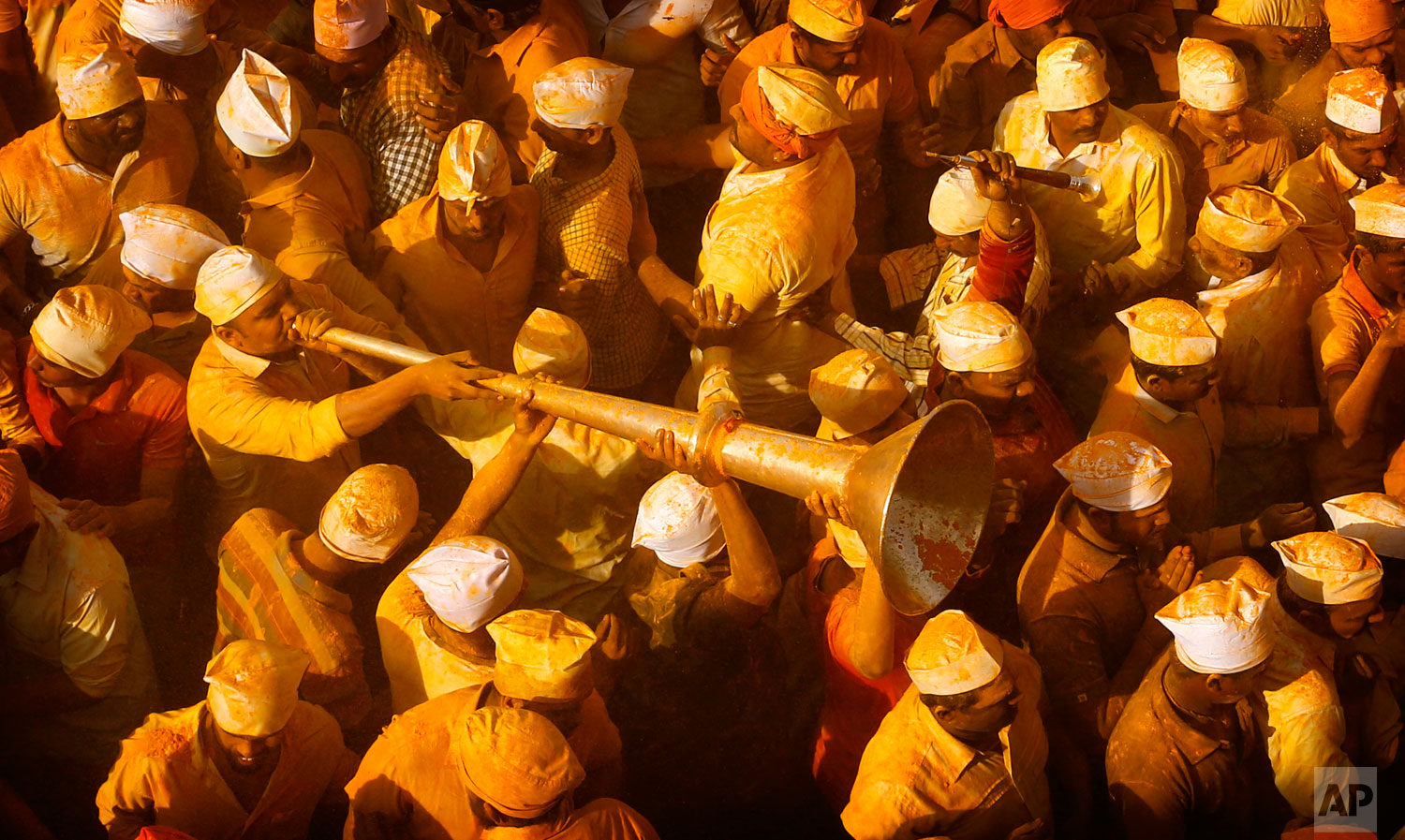 Devotee plays a horn in a crowd covered in the spice turmeric during the celebration of the Bhandara Festival, or the Festival of Turmeric, at the Jejuri temple in Pune district, Maharashtra state, India. During the festival, devotees use the golden powder to worship the deity Lord Khandoba, widely known as a descendant of the sun, and to celebrate his victory over the demons Mani and Malla. (AP Photo/Rafiq Maqbool)