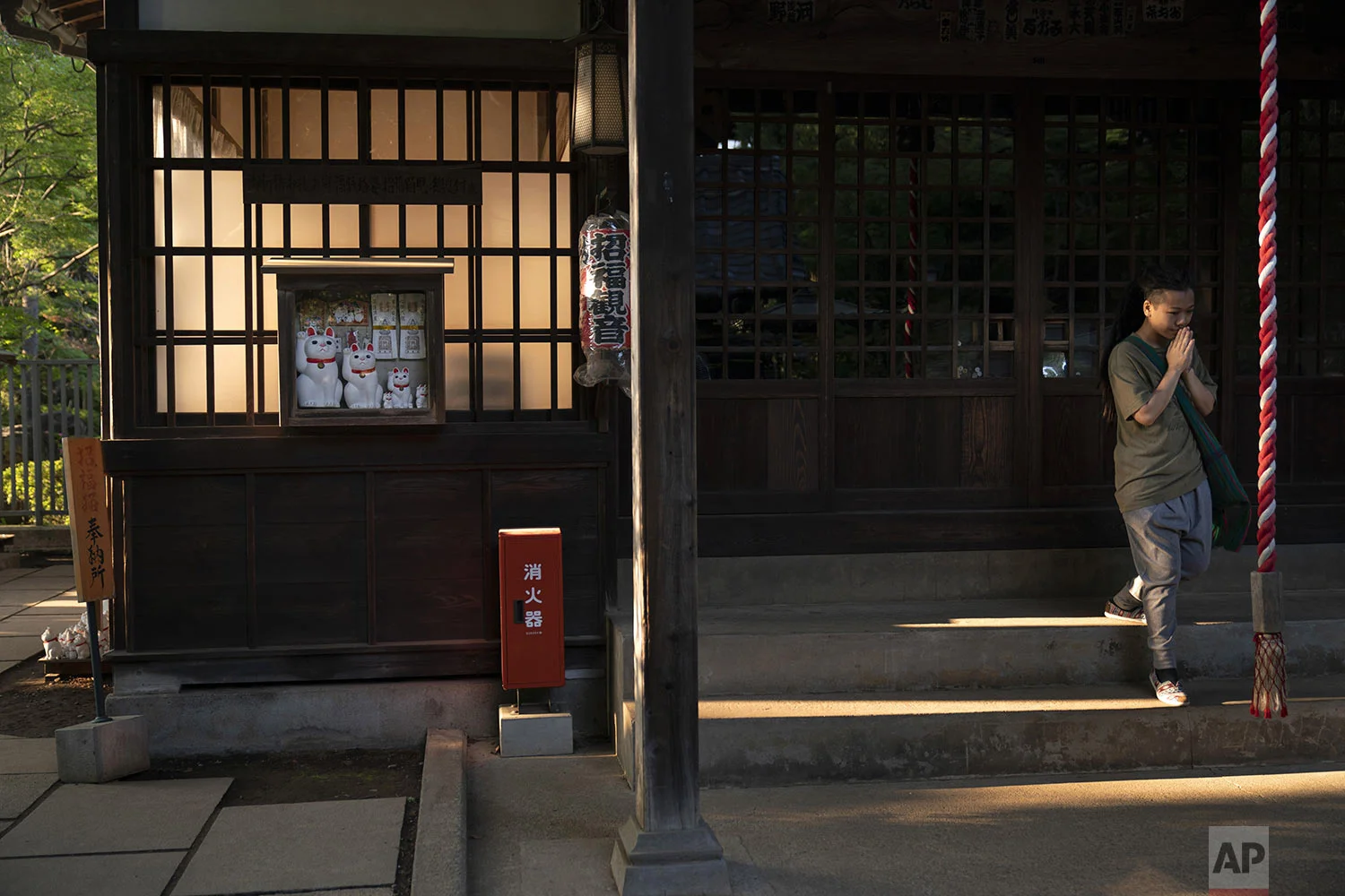 A tourist visiting from Hong Kong prays at Gotokuji Temple in Tokyo, Tuesday, June 25, 2019. (AP Photo/Jae C. Hong)